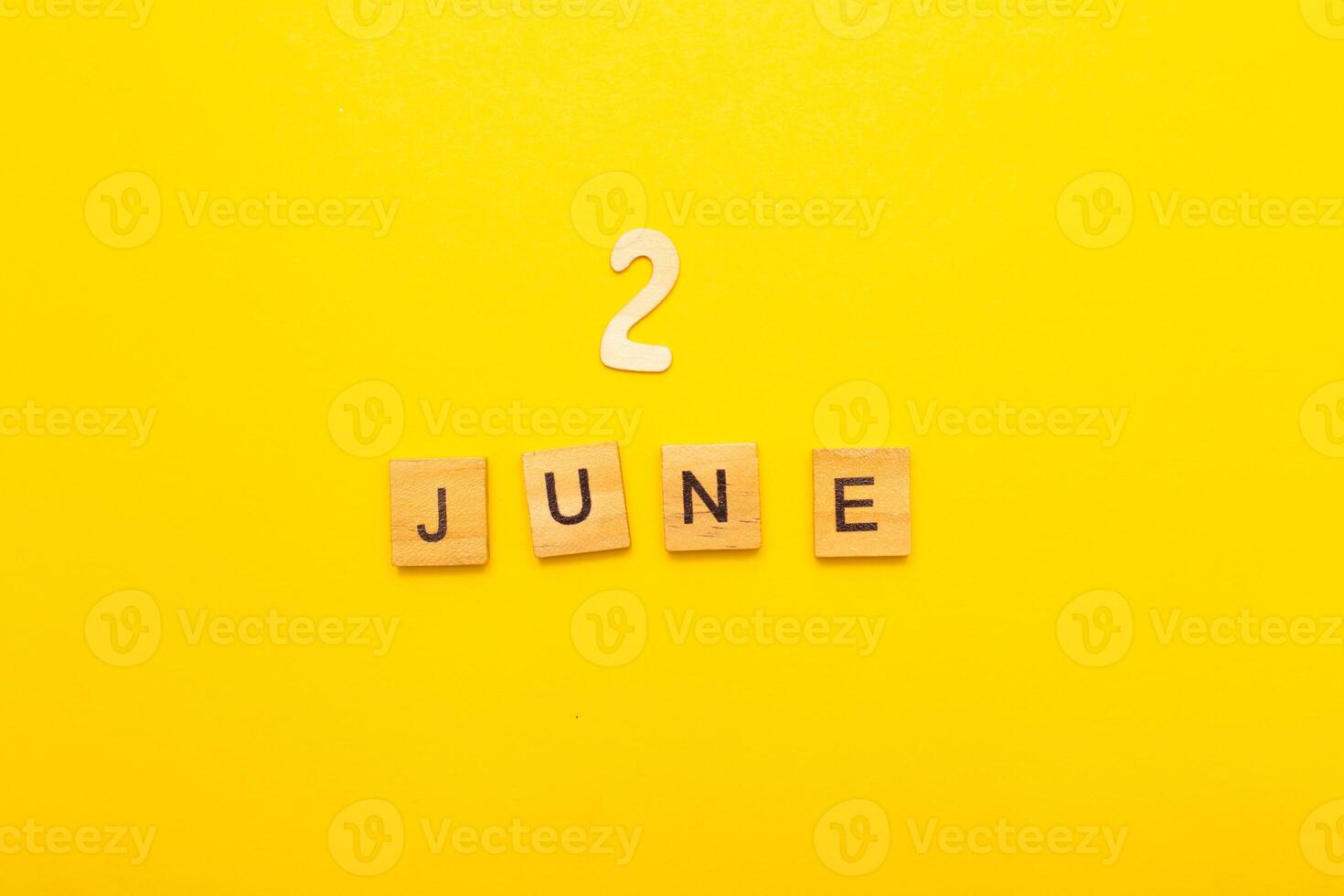 Top view of word 2 June calendar date made by wooden cubes on yellow color background photo