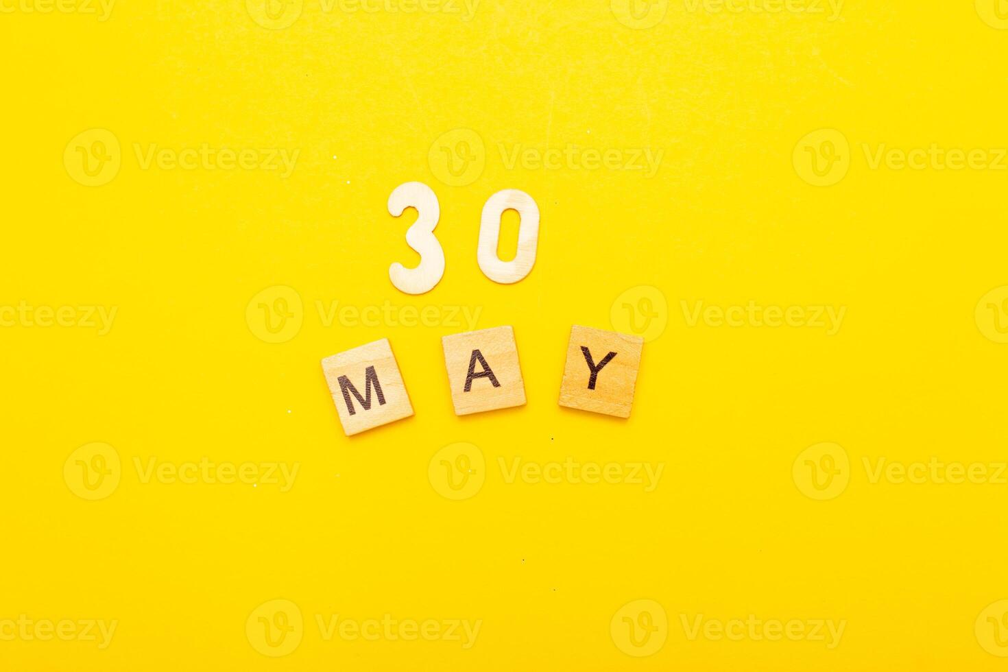 Top view of word 30 May calendar date made by wooden cubes on yellow color background photo