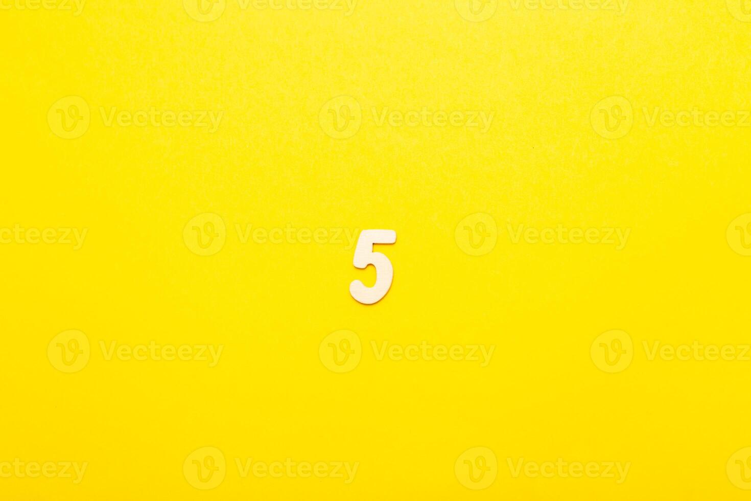 Top view of wooden number 5 five on yellow bright background. photo