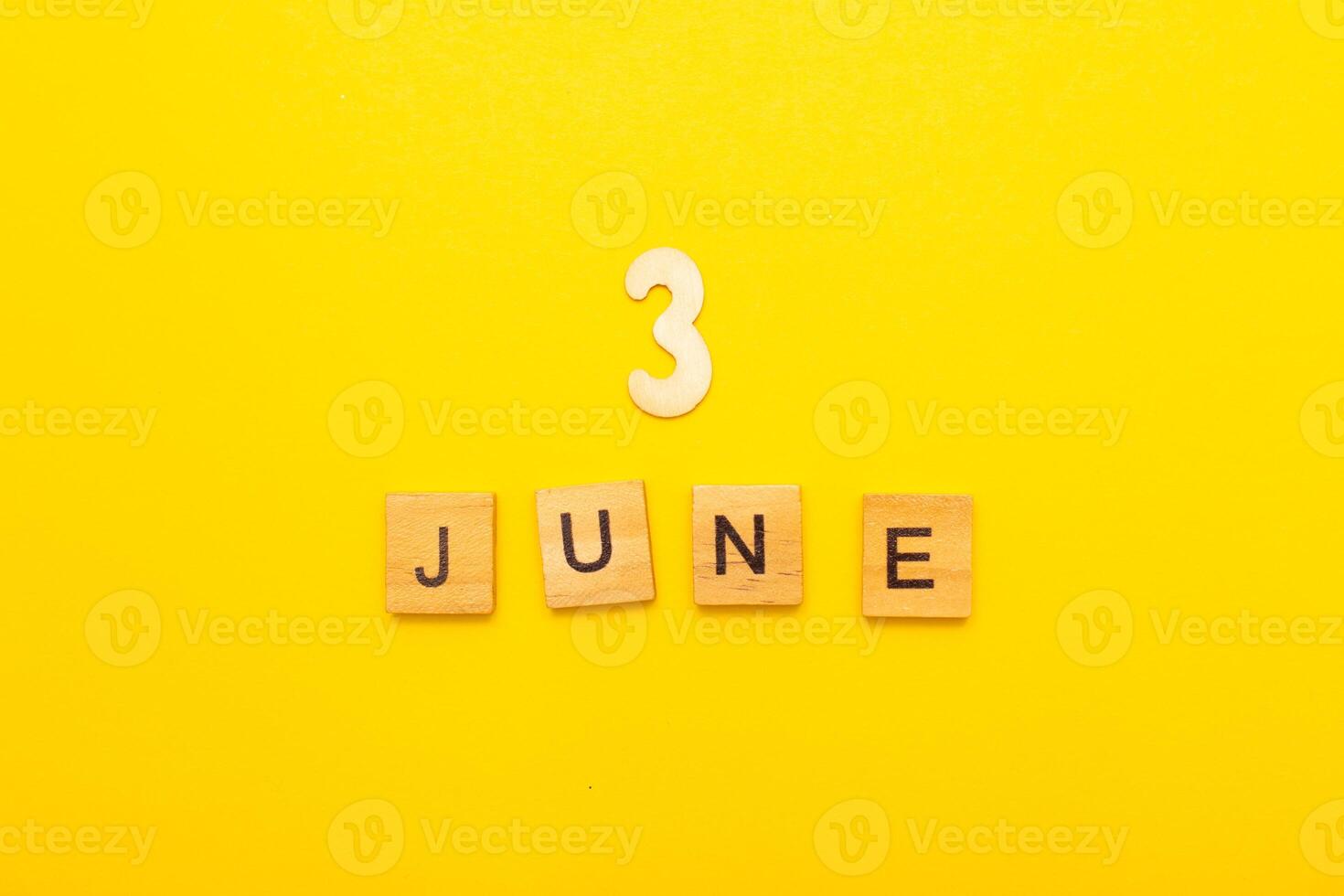 Top view of word 3 June calendar date made by wooden cubes on yellow color background photo
