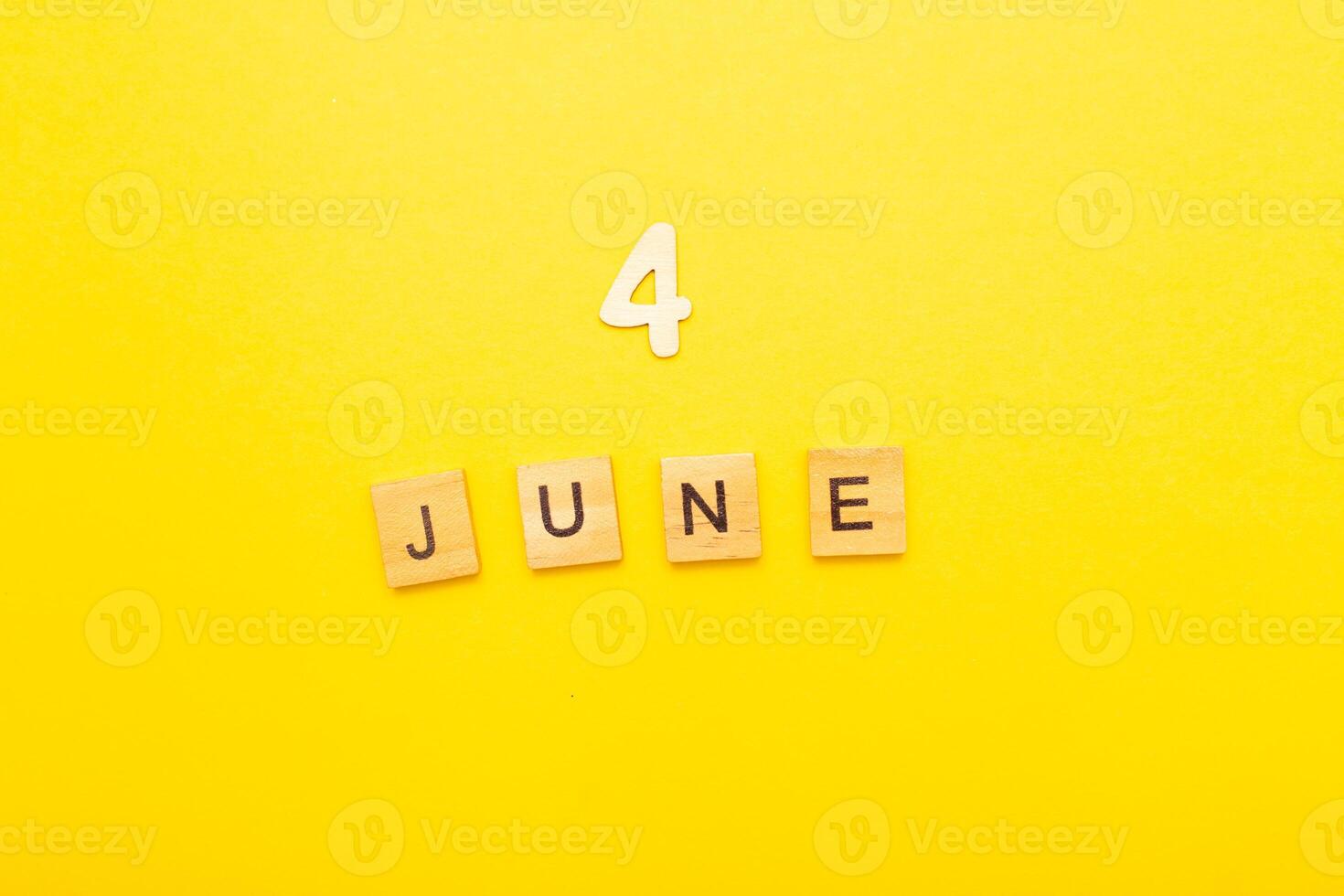 Top view of word 4 June calendar date made by wooden cubes on yellow color background photo
