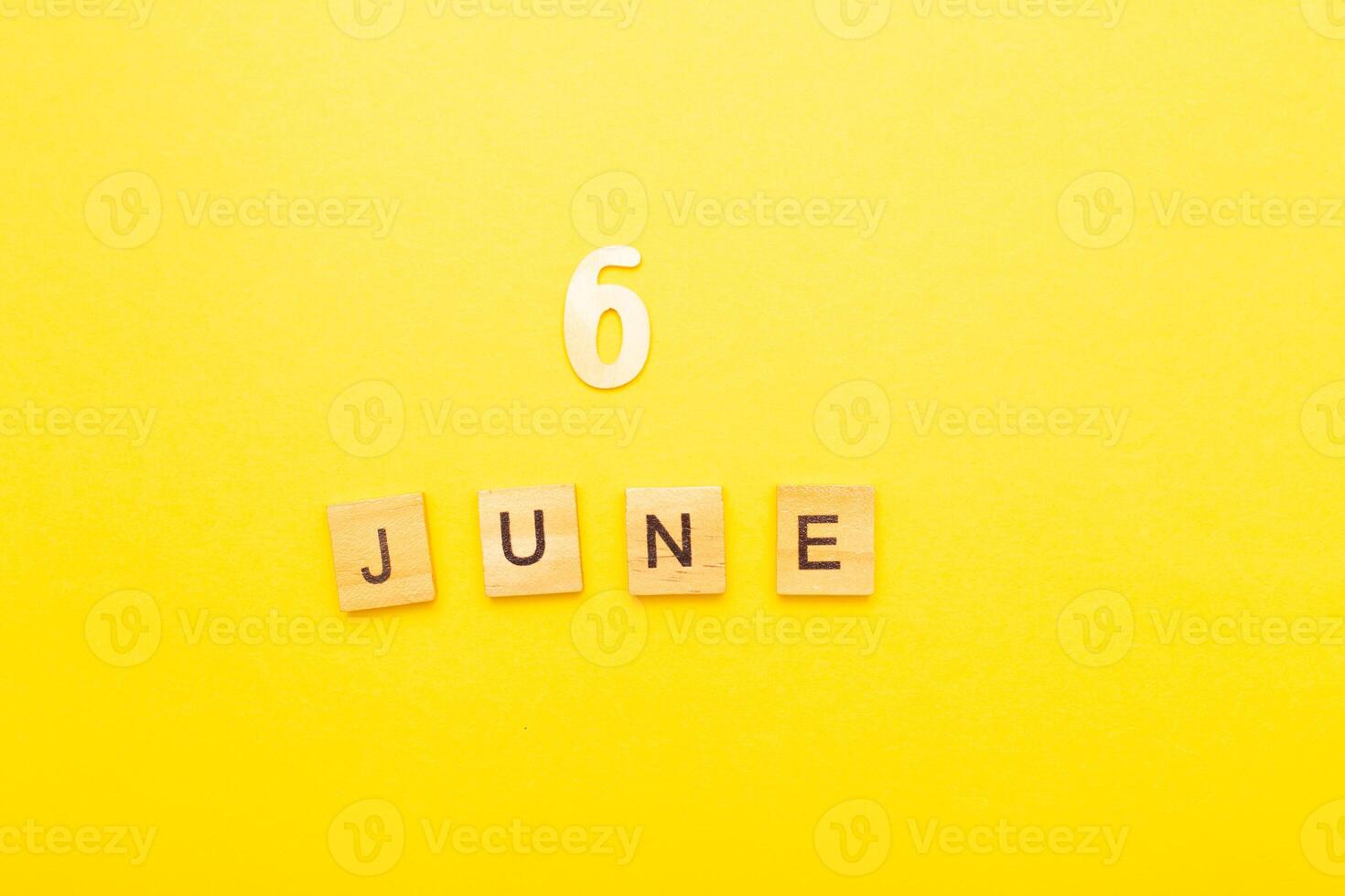 Top view of word 6 June calendar date made by wooden cubes on yellow color background photo