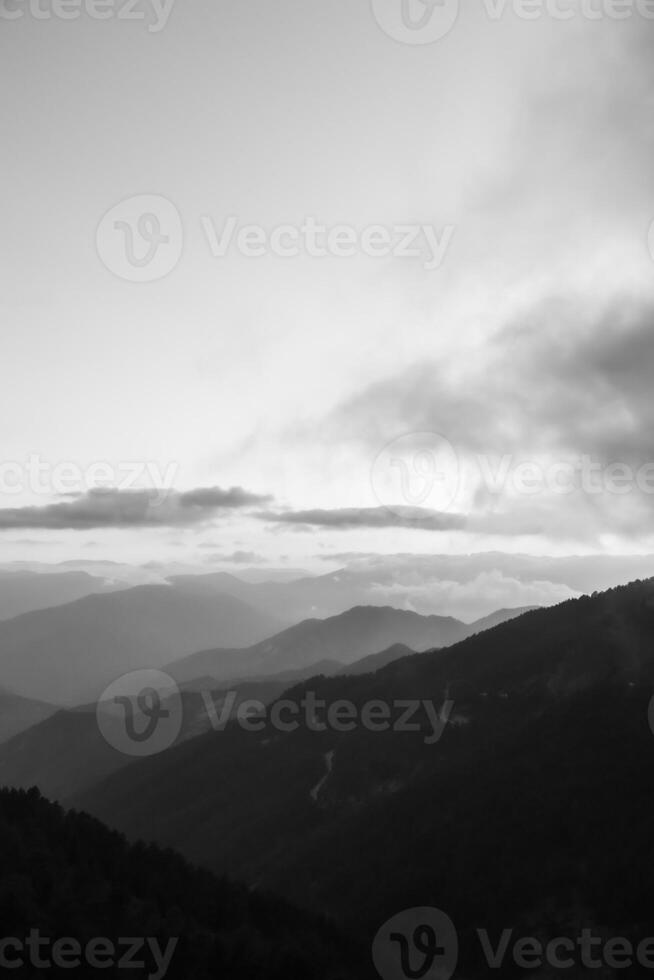 Black and wihte landscape photo of the mountain range with mist