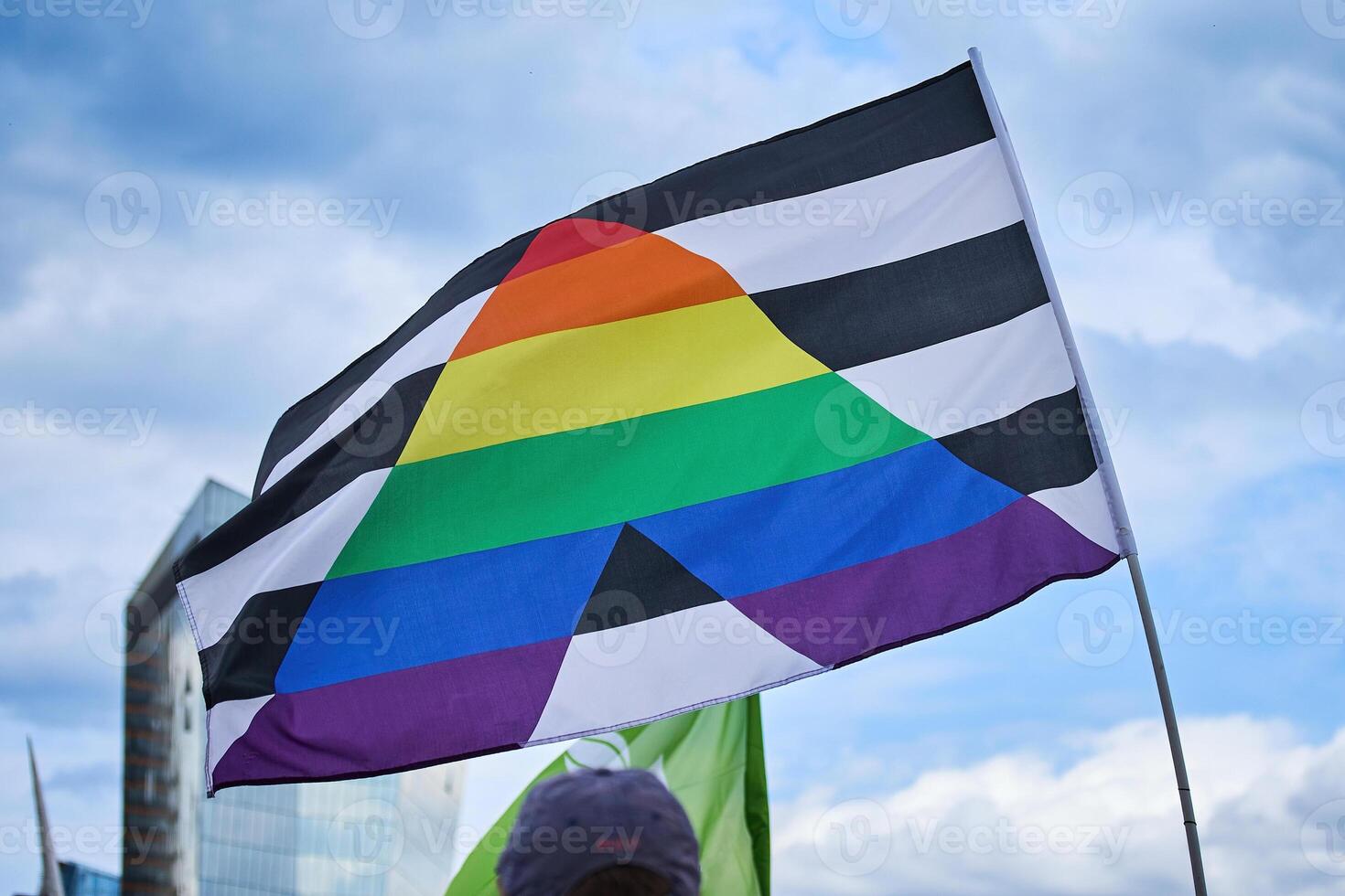 Pride Flag Against Sky. A pride flag with black and white stripes and rainbow triangle photo