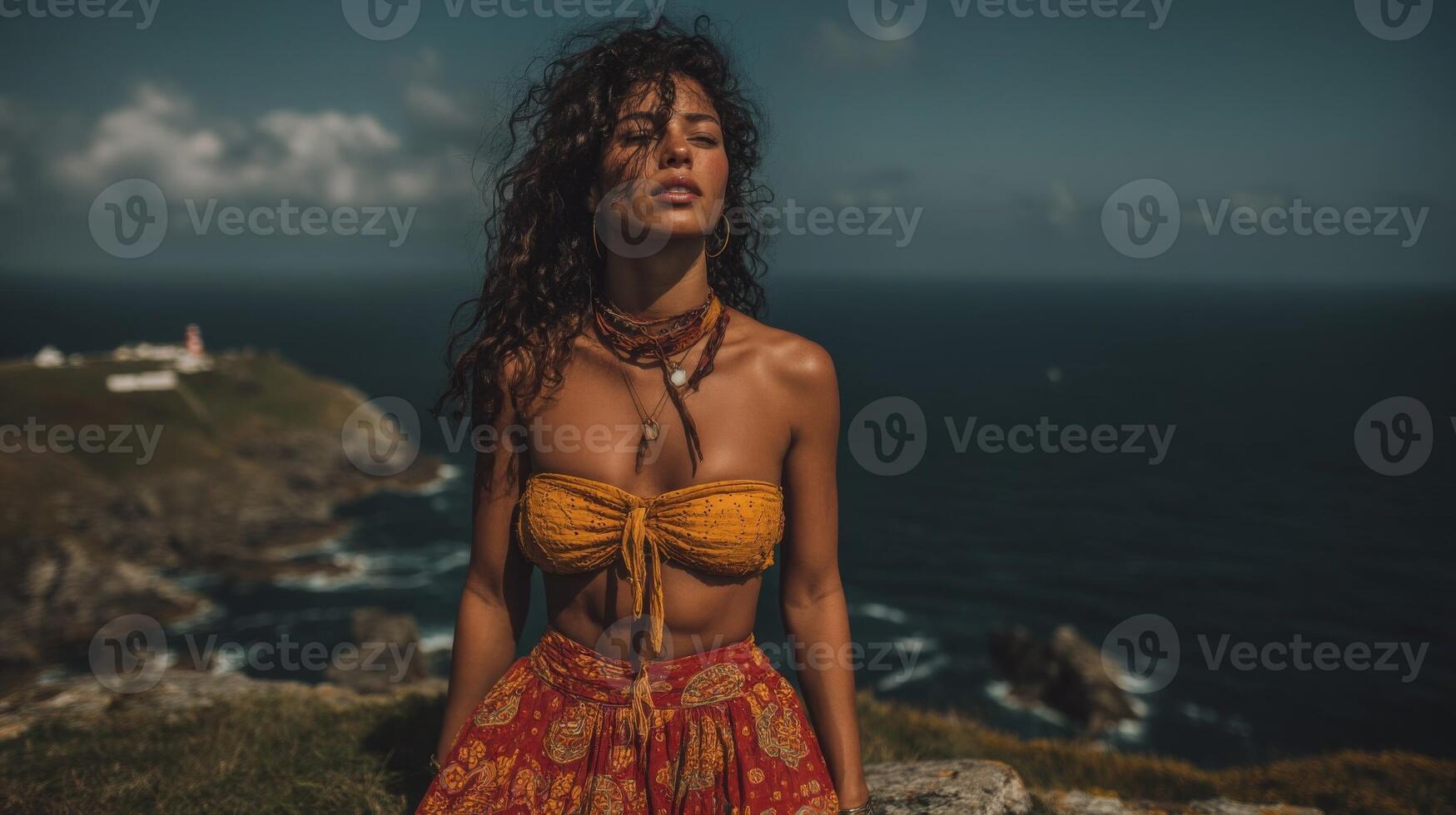 Woman with Curly Hair in Yellow Top and Red Dress on Ocean Cliff photo