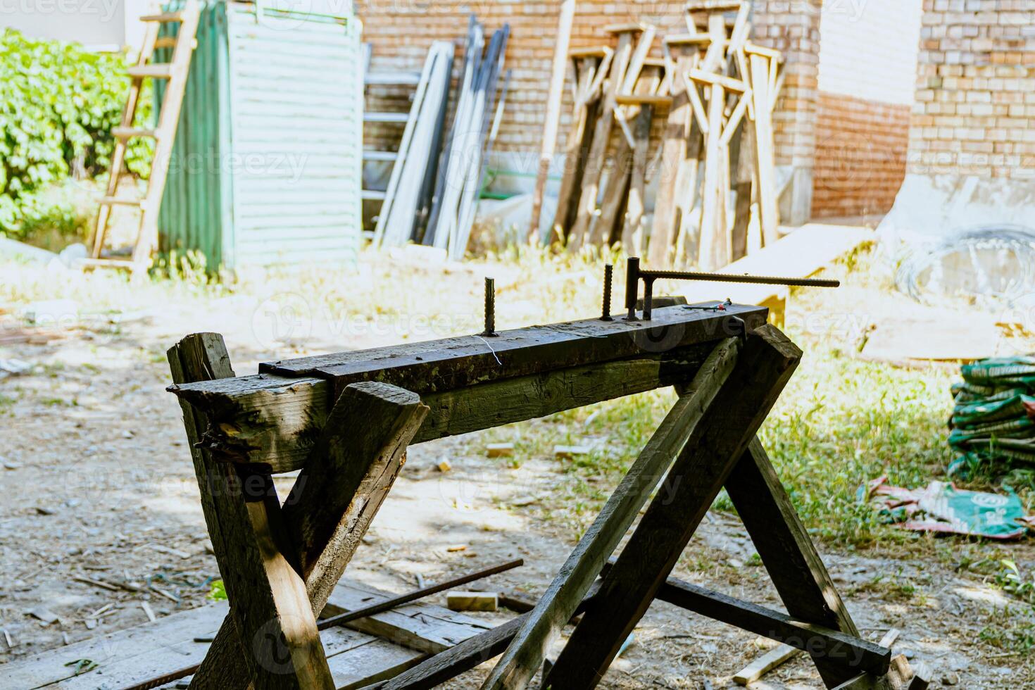A bench with a saw and other tools in a yard photo