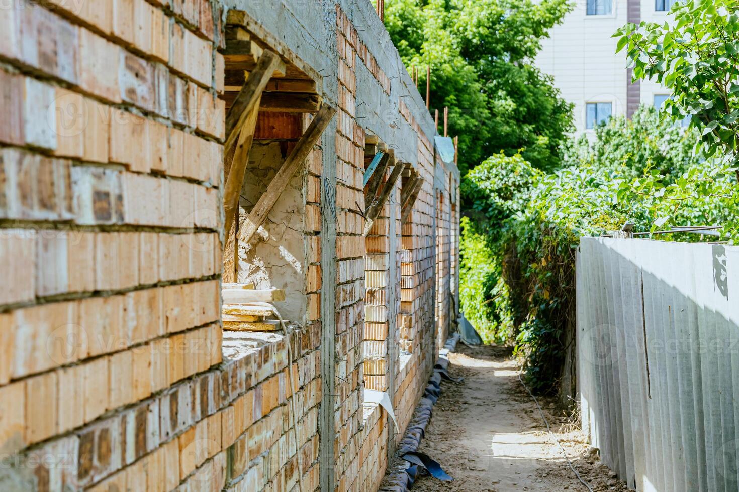 A brick wall with a fence and a tree photo