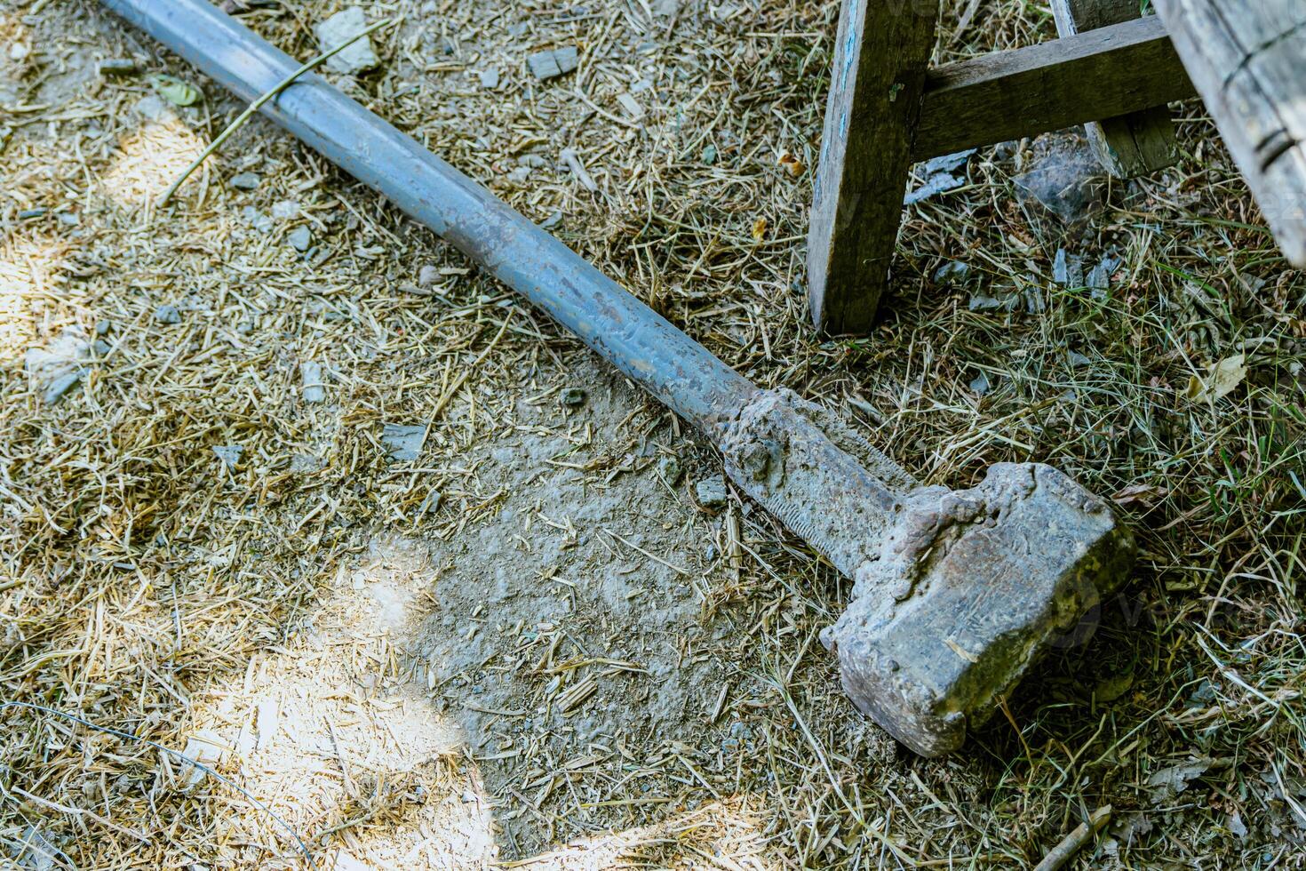 A large axe laying on the ground next to a bench photo