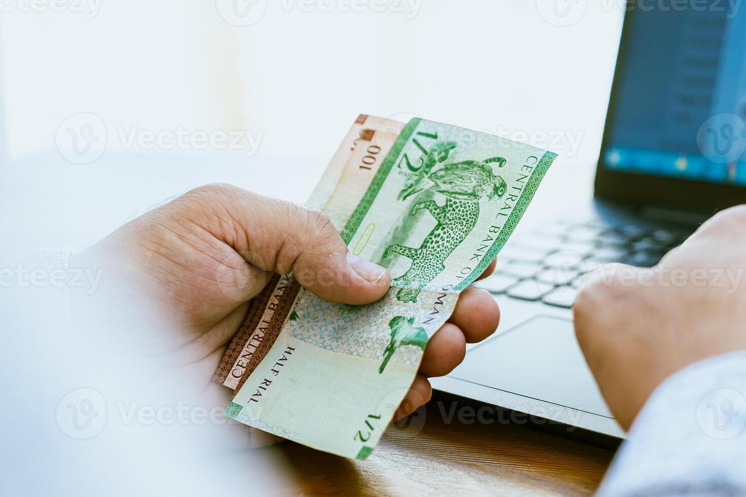 A man holding a bank note and a laptop computer photo