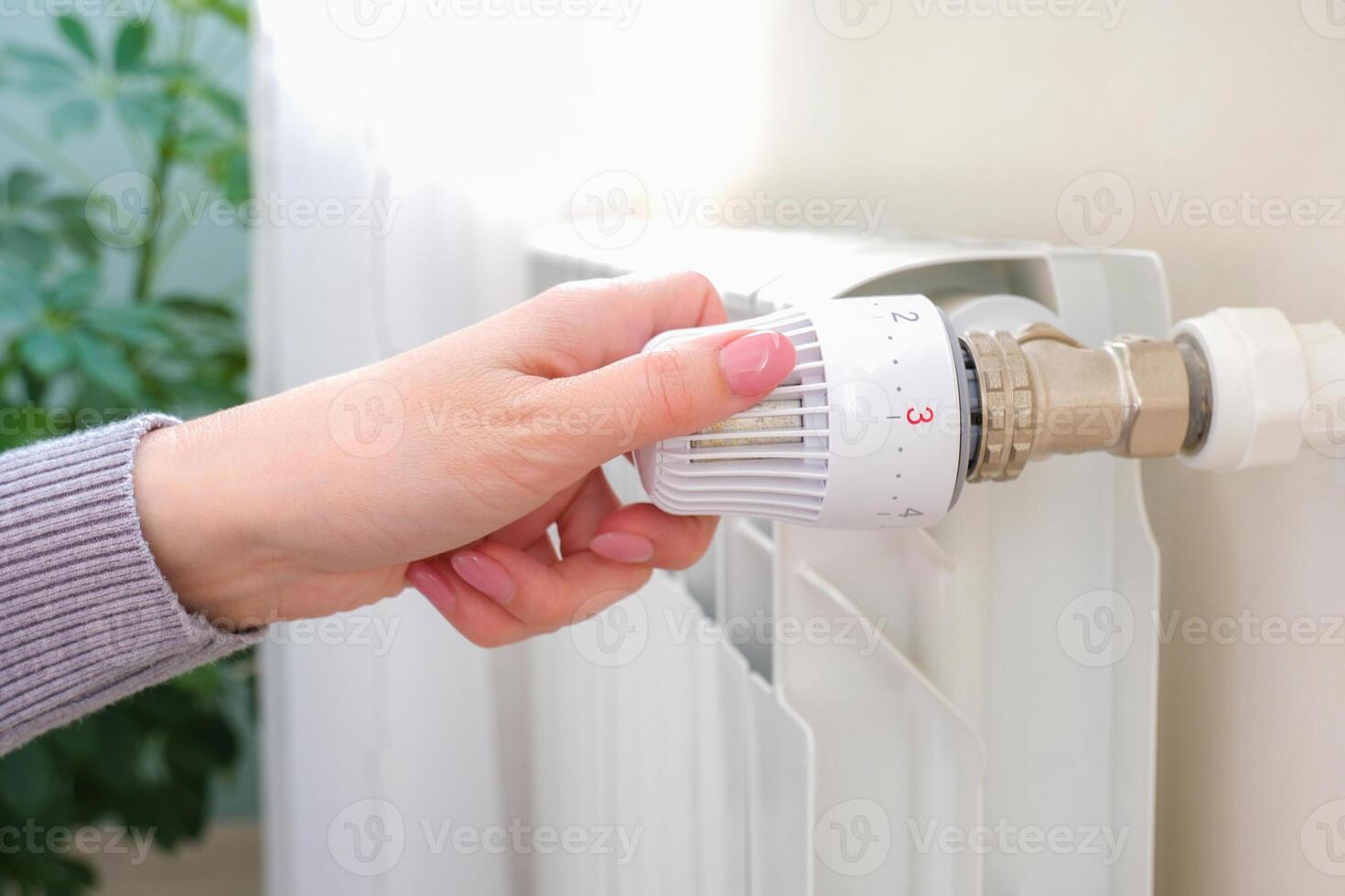 The heat regulator on the radiator of the house. A woman regulates the heat level in the radiator photo