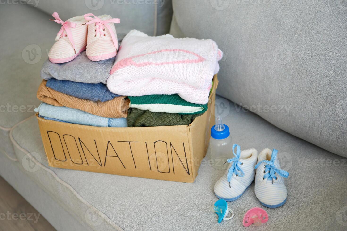 Donation box with clothes for newborns on the couch photo