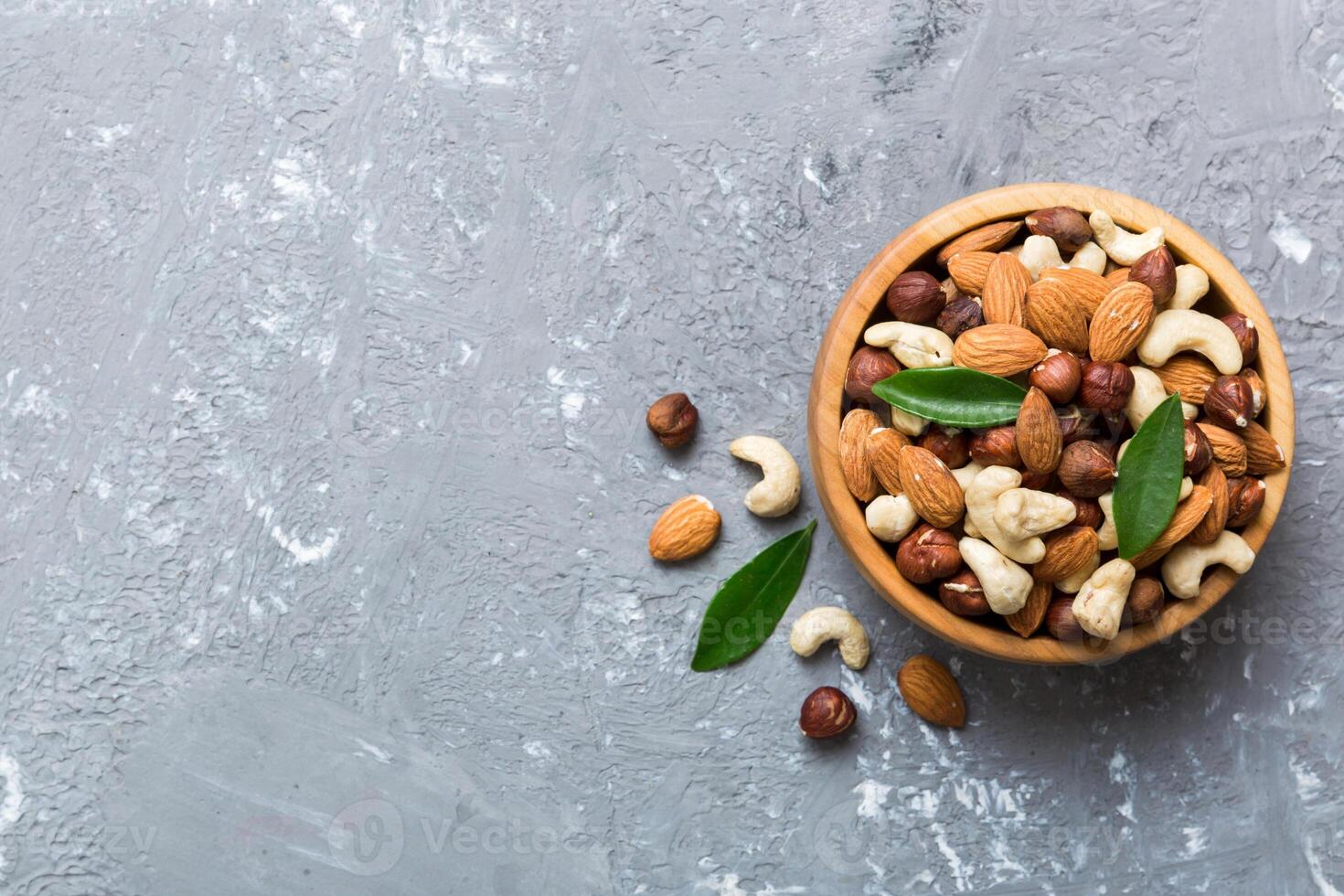 Assortment nuts wooden bowl colored table. Cashew, hazelnuts, walnuts, almonds. Mix of nuts Top view photo