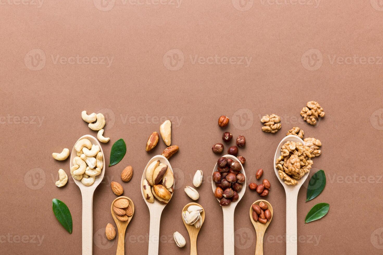 mixed nuts in white wooden spoon. Mix of various nuts on colored background. pistachios, cashews, walnuts, peanuts and brazil nuts photo