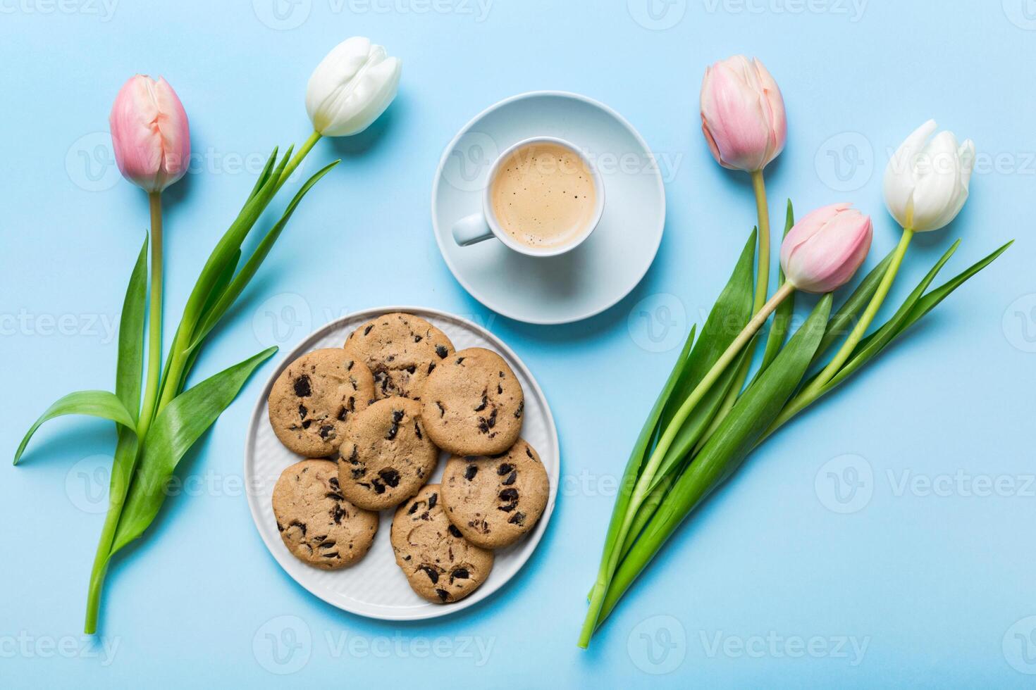 Cup of coffee mug with coffee, cookies and tulips on a colored background. Greeting spring card photo