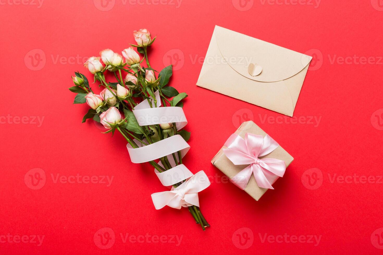 Greeting card mockup with copy space, pink ribbon and roses flowers on colored table background. Flat lay, mother day holiday concept photo