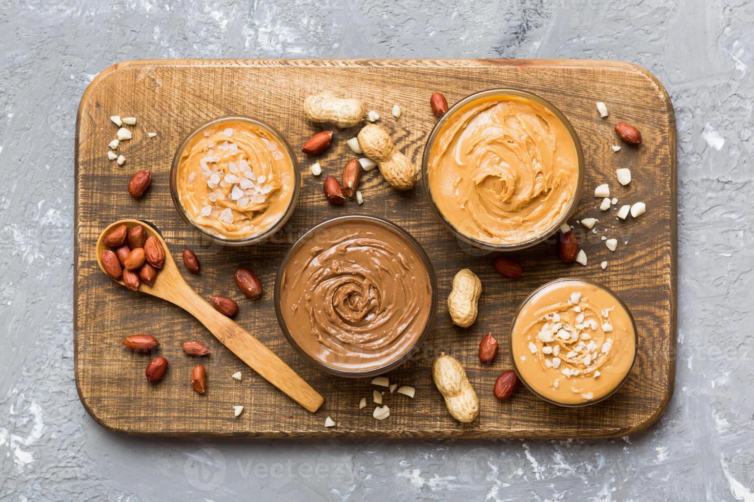 Glass jar with peanut butterin plate on table background, top view space for text photo