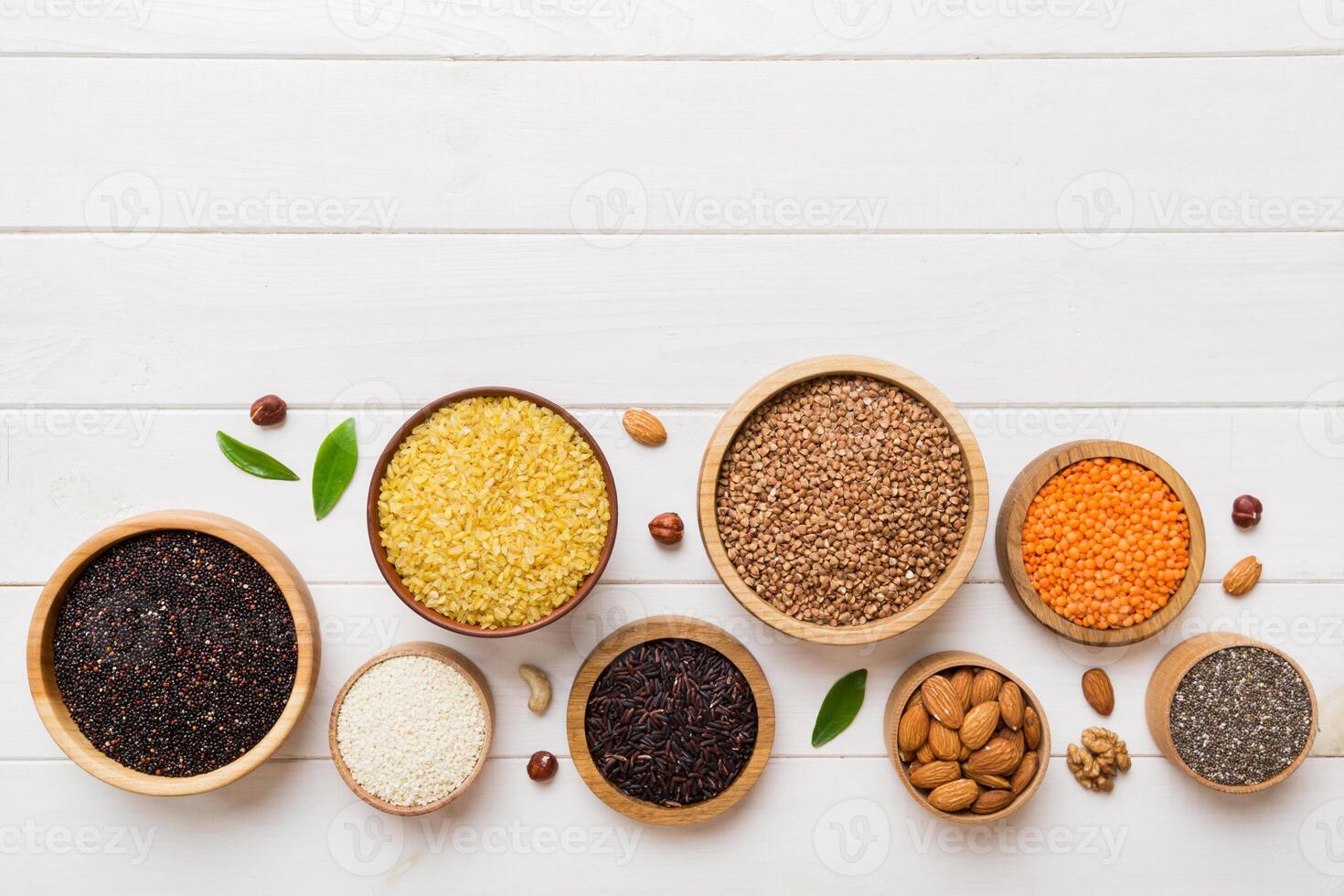 Various superfoods in smal bowl on colored background. Superfood as rice, chia, quinoa, lentils, nuts, sesame seeds, almonds. top view photo
