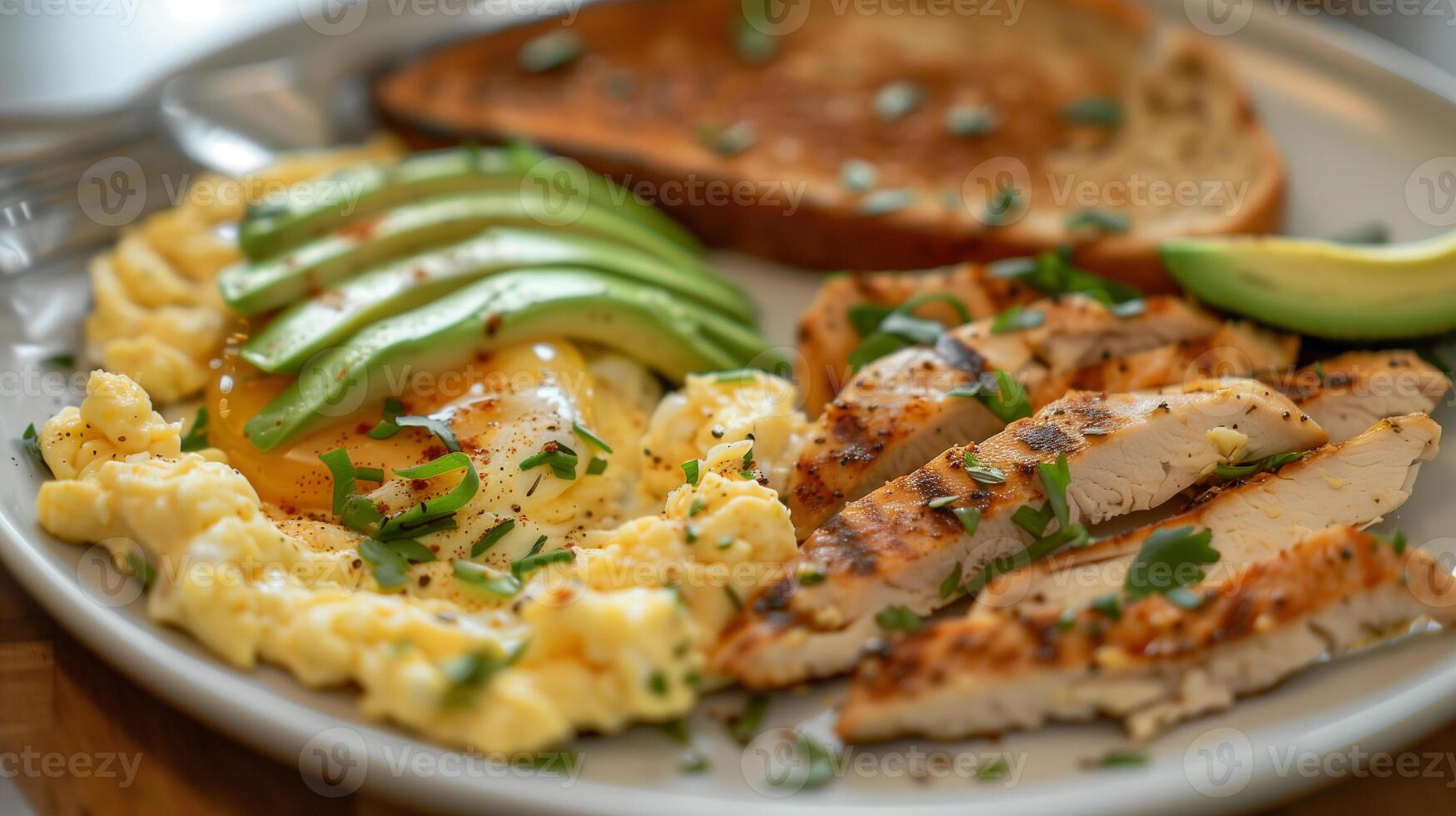 This Savory chicken, scrambled eggs, and avocado with whole grain toast for wellness. photo