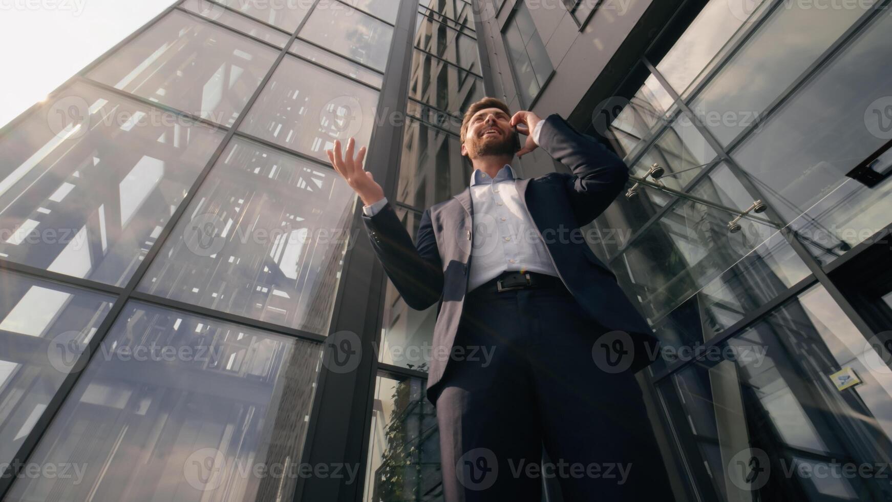 Bottom view smiling successful business man talking mobile phone happy discuss work deal with smartphone businessman male speaking cellphone consulting client communicate in city near office building photo