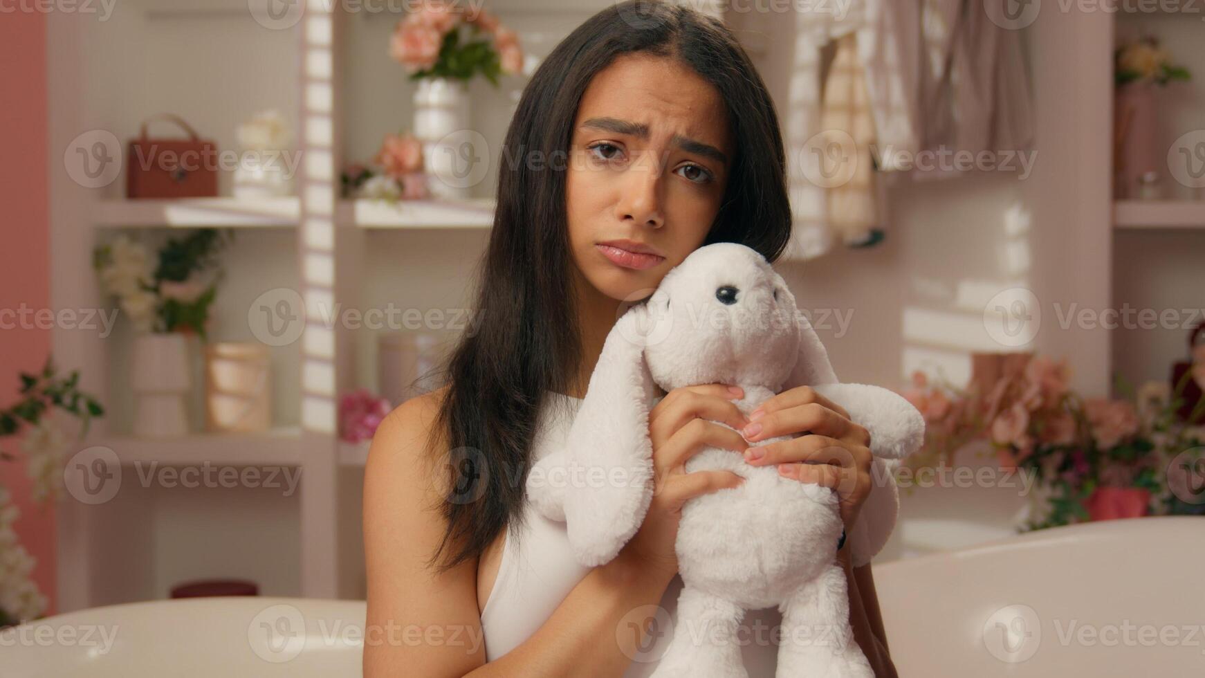 Offended sad upset Hispanic woman Latina America ethnic girl worried female daughter custody teenager in bathroom home hugging soft toy fluffy rabbit suffering problem family divorce domestic violence photo