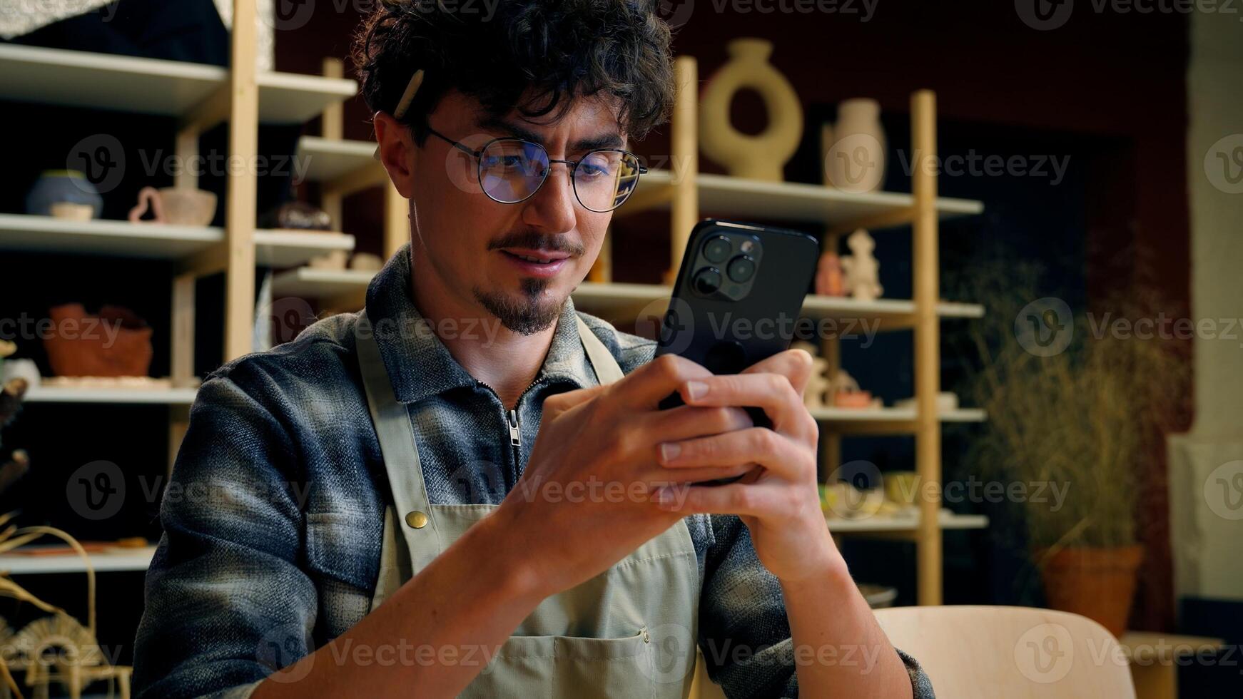 Man potter sculptor artisan take photo on mobile phone handmade crockery selling online in pottery workshop small business owner blogger influencer blog craft sales ceramics marketing craftsman hobby