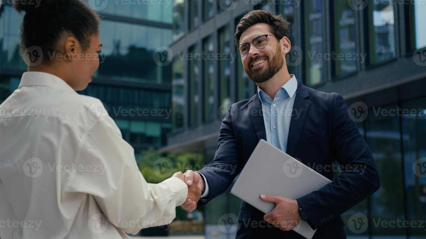 Two multiethnic business people colleagues handshaking in city diversity Caucasian businessman handshake with African American businesswoman shaking hands man woman recruit partnership cooperation photo