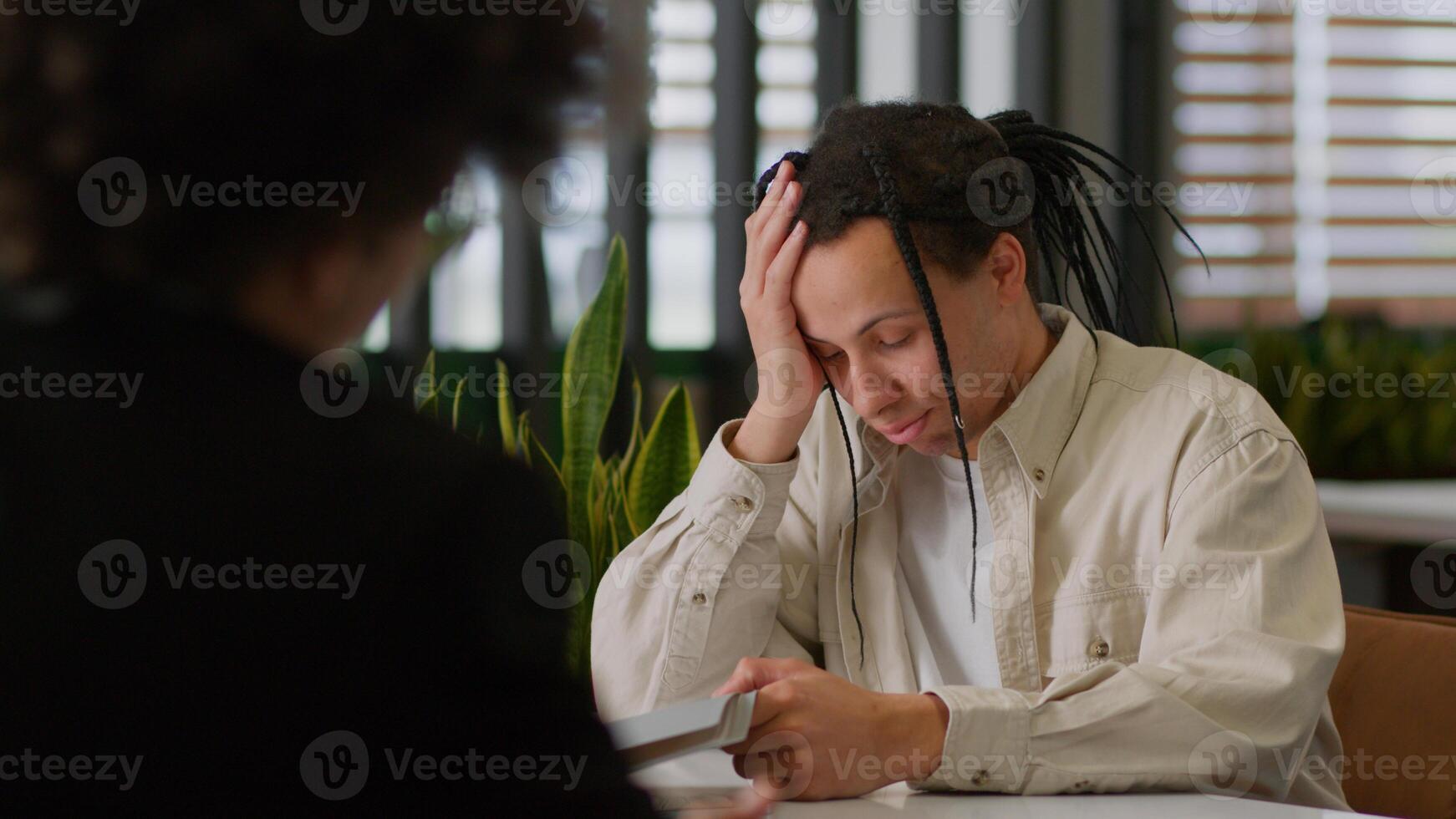 Ethnic business guy intern man male in office getting rejected for job upset back view African American leader boss giving folder with documents papers bad result two businessmen paperwork problem photo