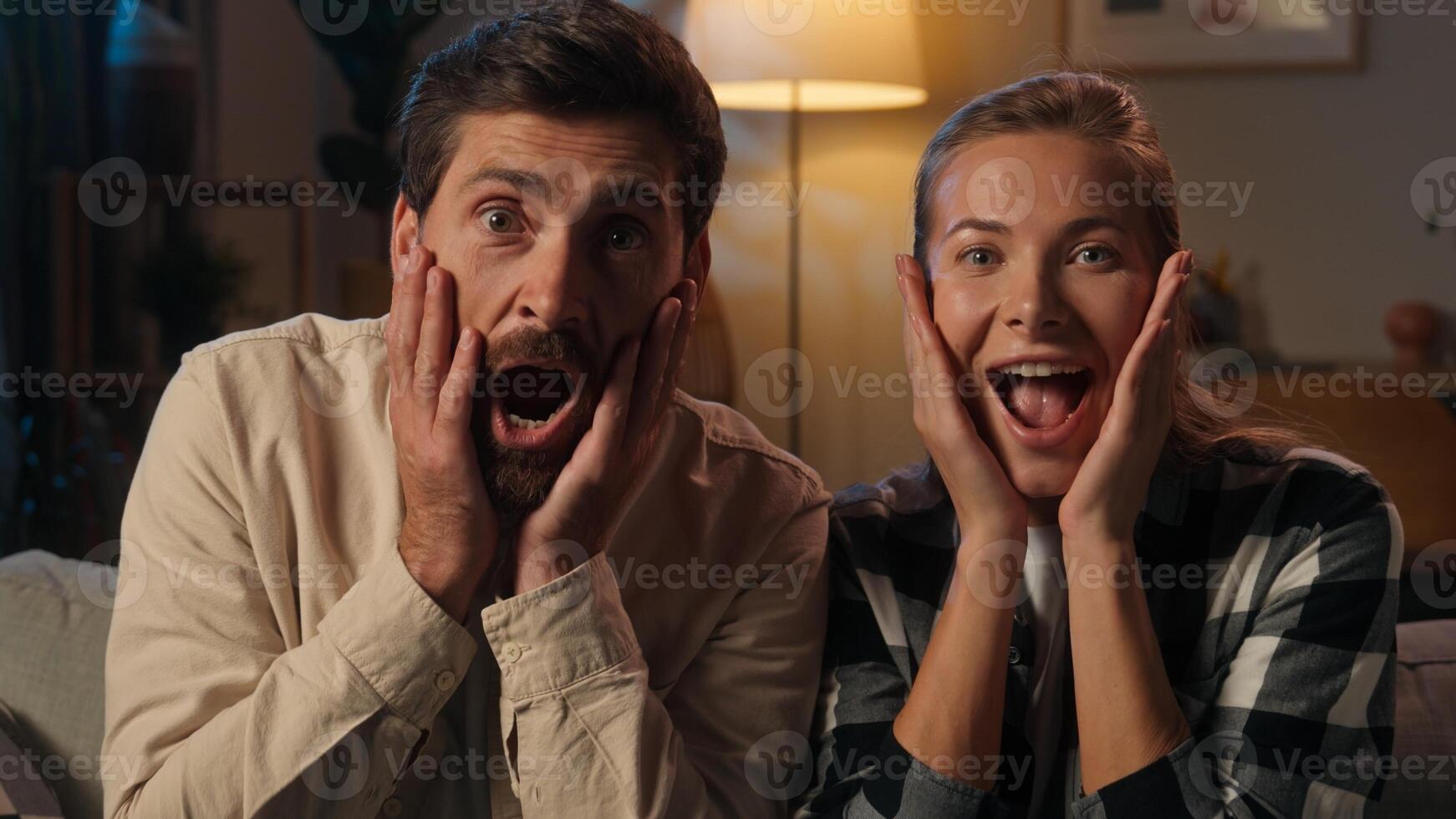Caucasian woman man shocked surprised family husband wife couple looking at camera evening night at home positive millennials shock open mouth surprise wonder amazing good news wow emotions excited photo