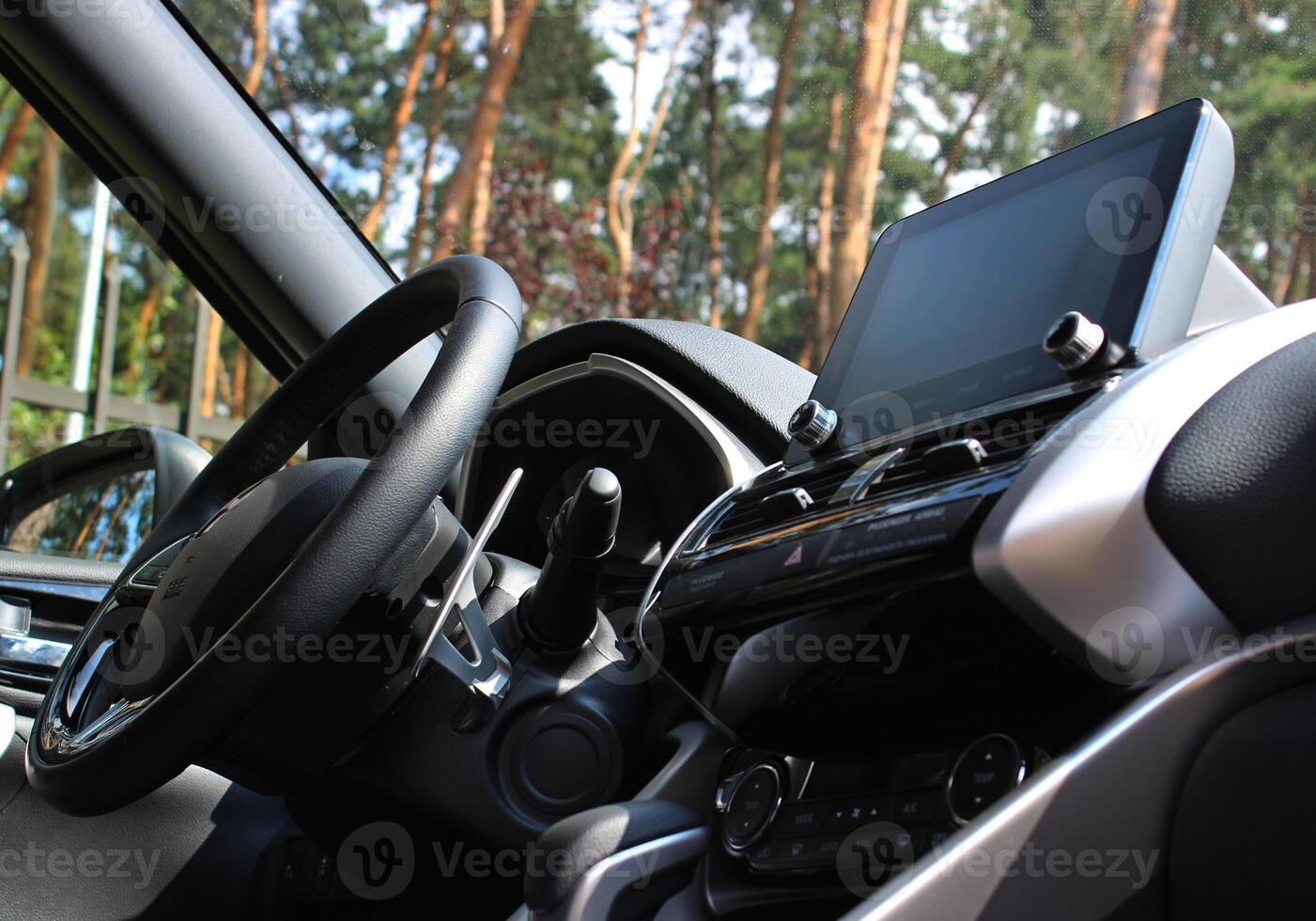 Bottom view of steering wheel and central dashboard of car parked in forest photo