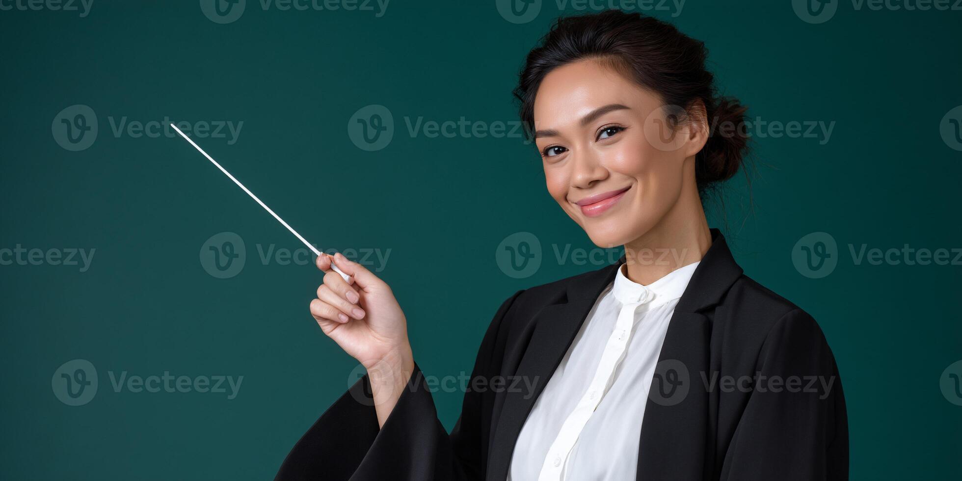 Confident woman in business attire holds a baton, smiling warmly against a teal backdrop photo
