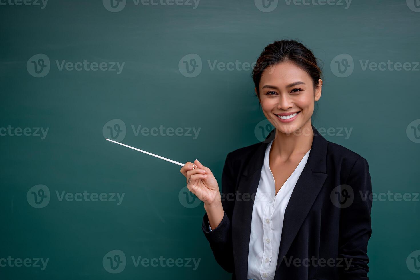 Smiling teacher points to chalkboard photo