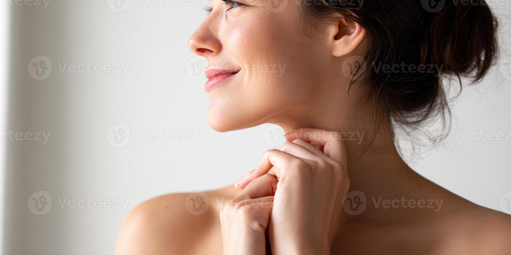 A woman is smiling and touching her neck photo