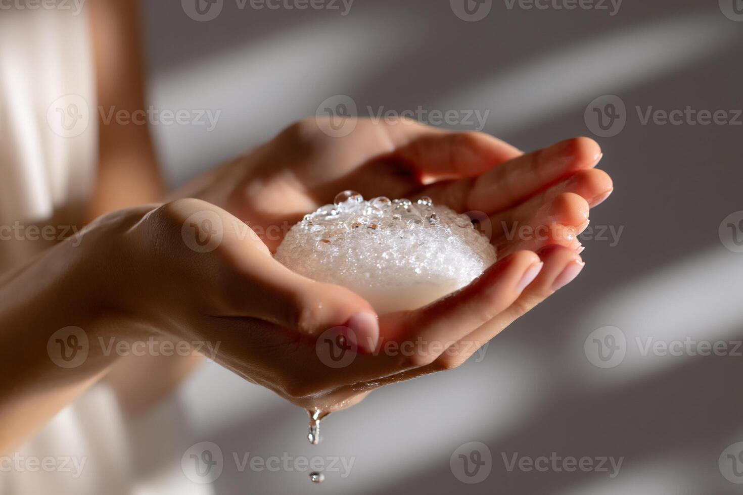 Close-up of hands holding a foamy soap bar, water droplets falling photo