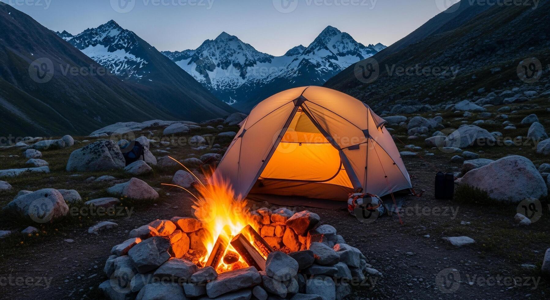 Illuminated Tent and Campfire in Mountain Valley at Dusk photo