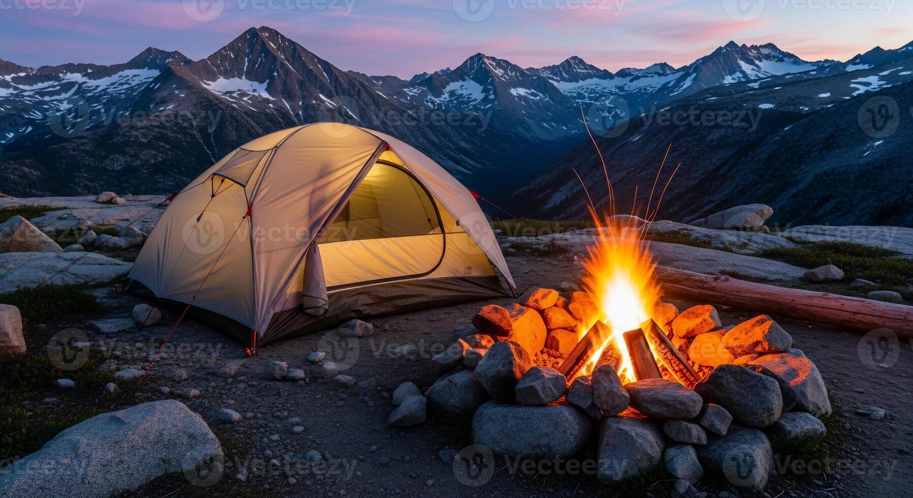 Illuminated Tent and Campfire Under Mountain Peaks at Dusk, Camping Adventure. photo