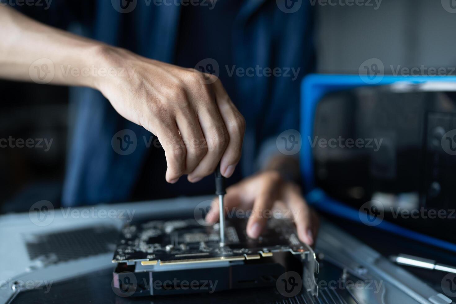 IT Engineer installing Hardware is repairing a computer with a screwdriver photo
