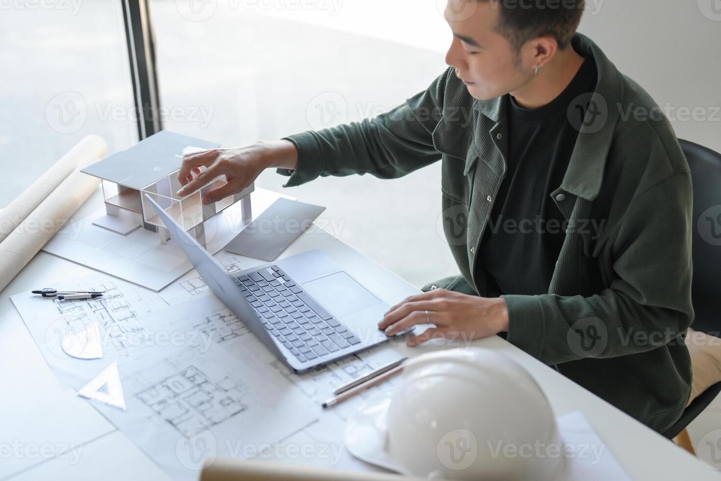 Architecture Man drawing on architectural working on a laptop at a table with construction plans photo