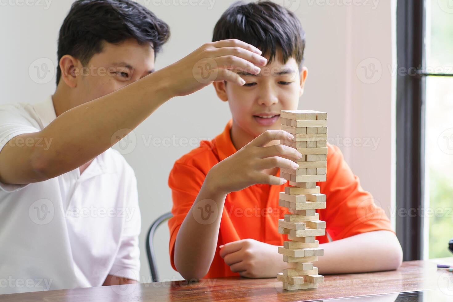 Asian father and son playing wood blocks game Carefree, kid playing wood blocks game building constructor from blocks with father at home. photo