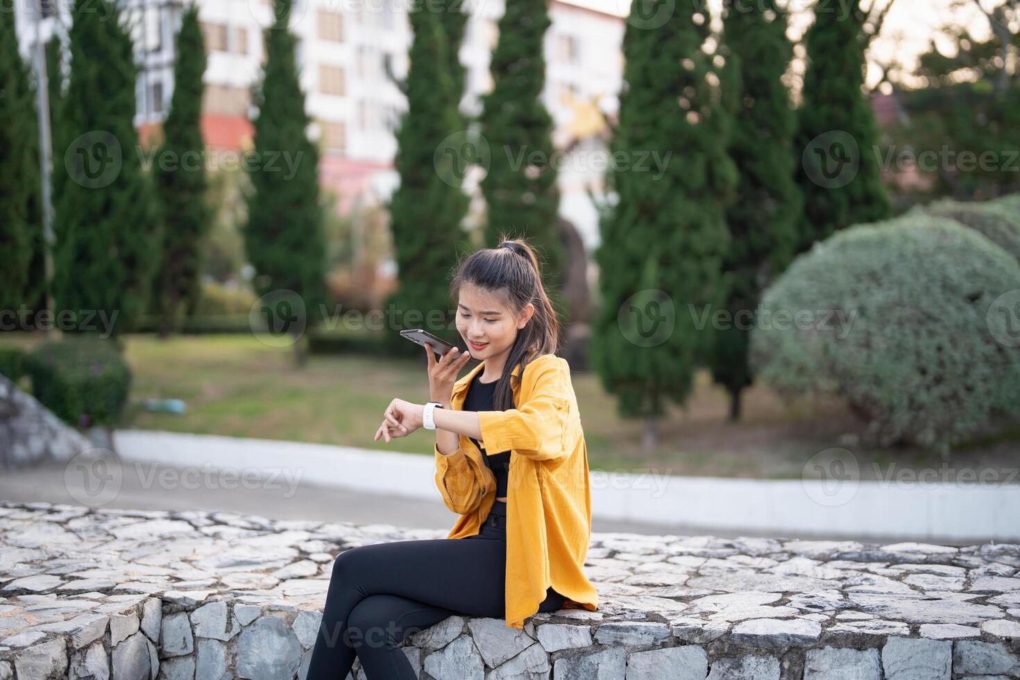 a woman sitting on a stone wall with her smartphone. photo