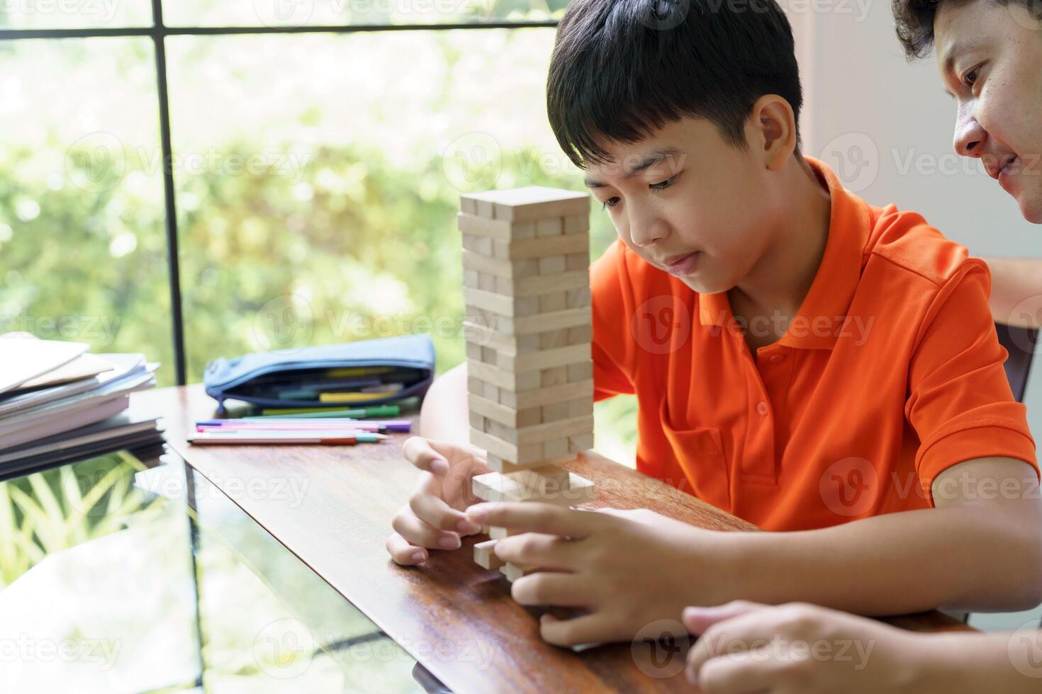 Asian father and son playing wood blocks game Carefree kid playing wood blocks game building constructor from blocks with father. photo