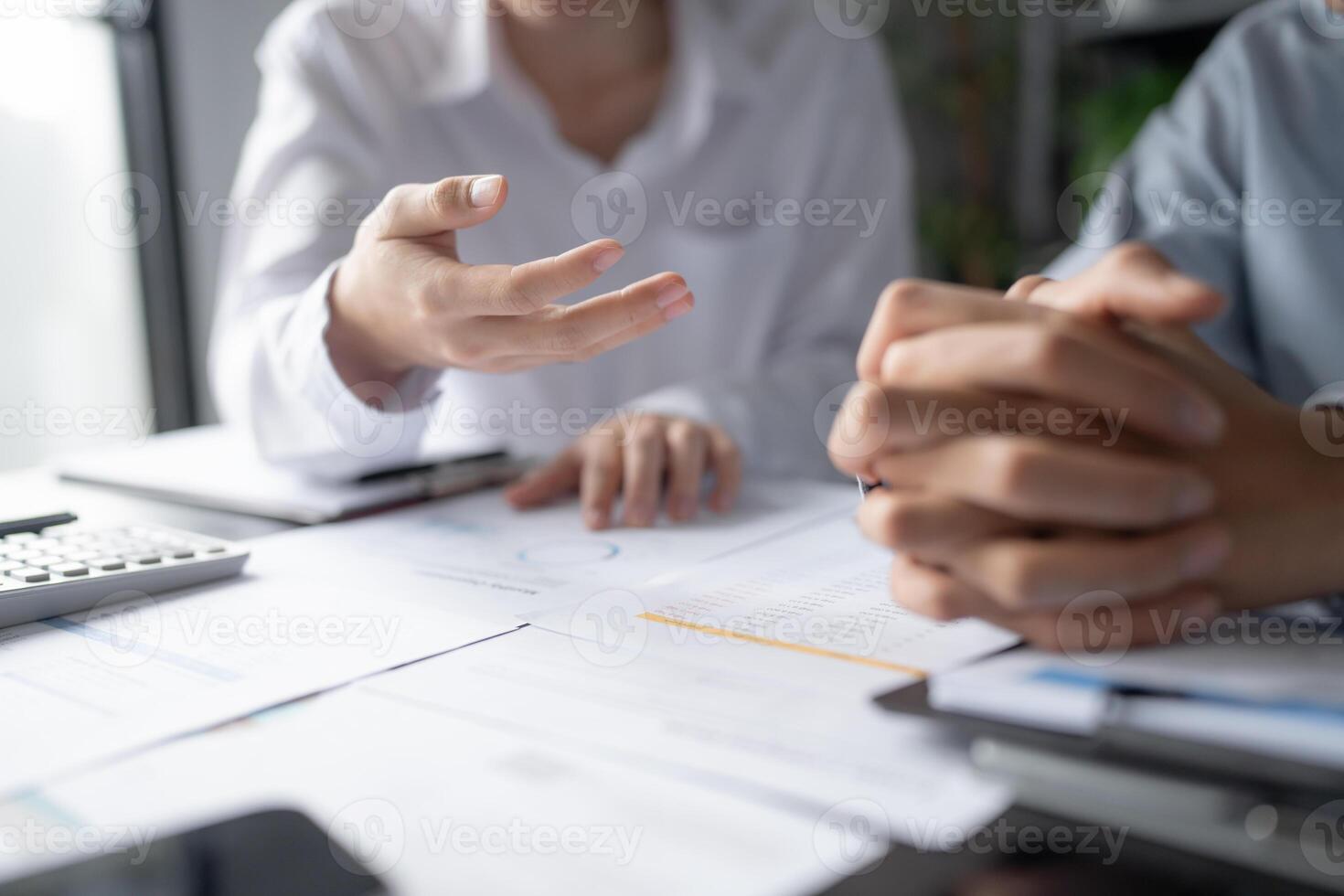 two business people sitting at a table with papers and a calculator photo