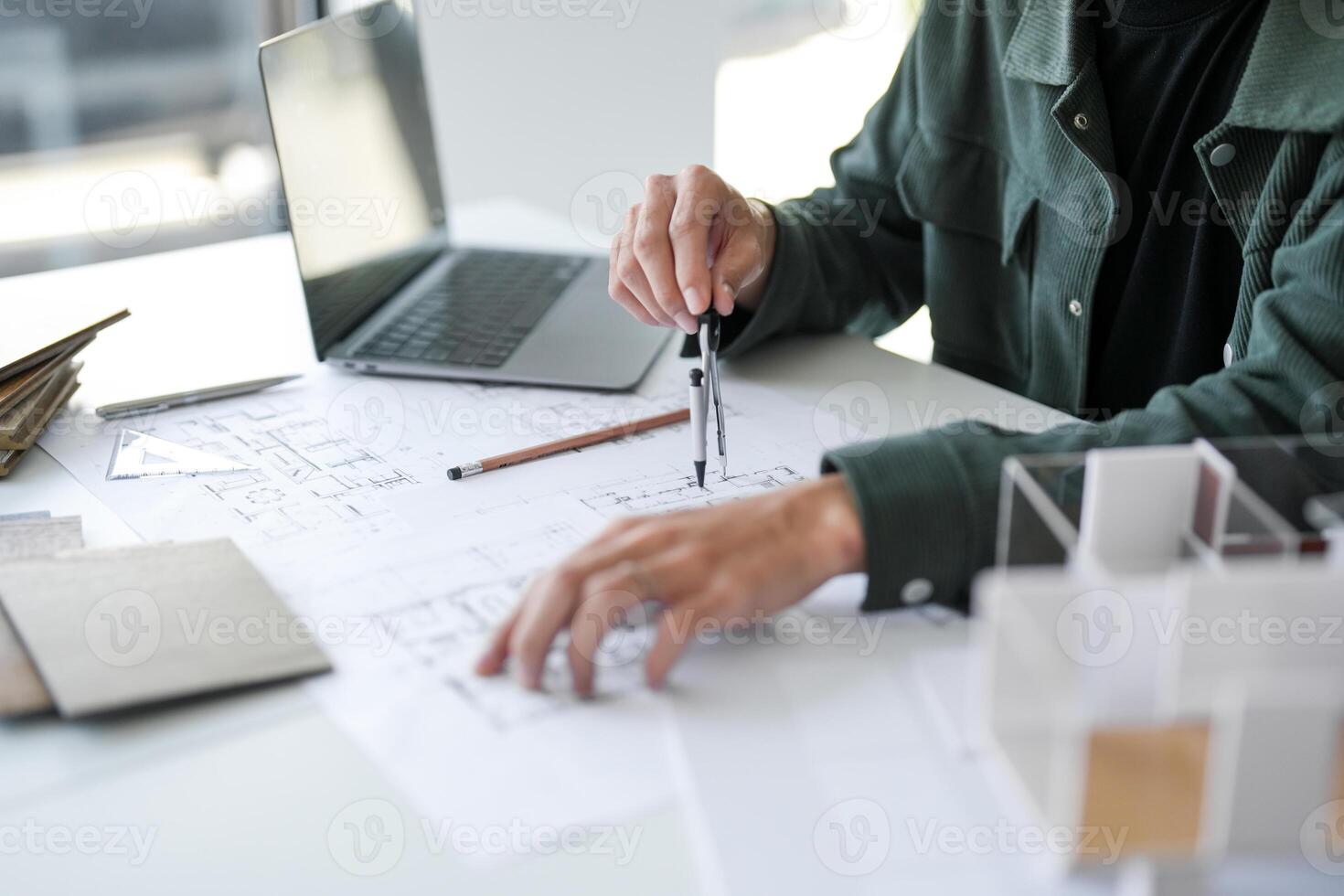 Architecture Man drawing on architectural working on a project with a laptop and a pencil photo