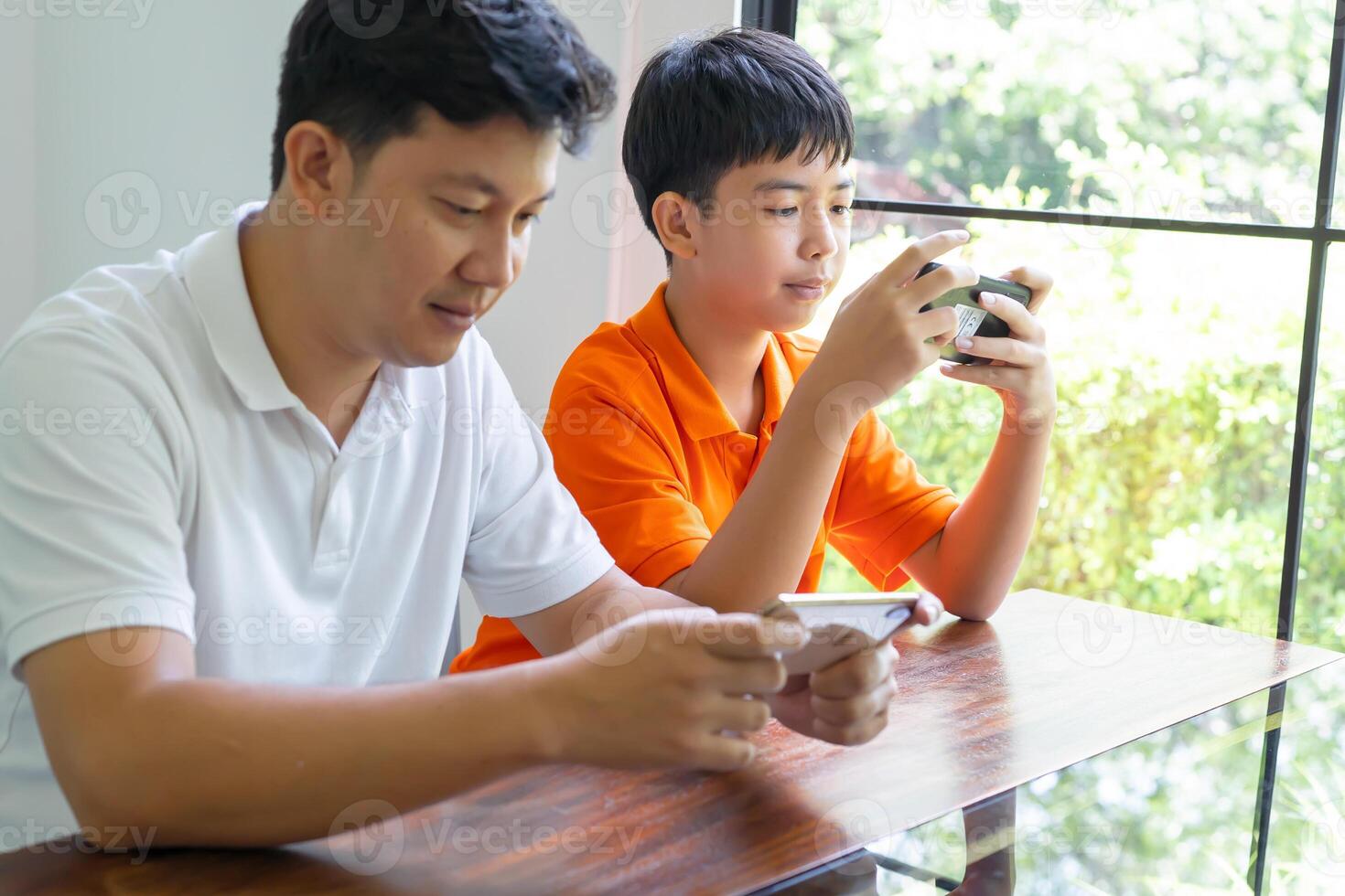 Asian father and son with mobile phone playing games together spend time with children family photo