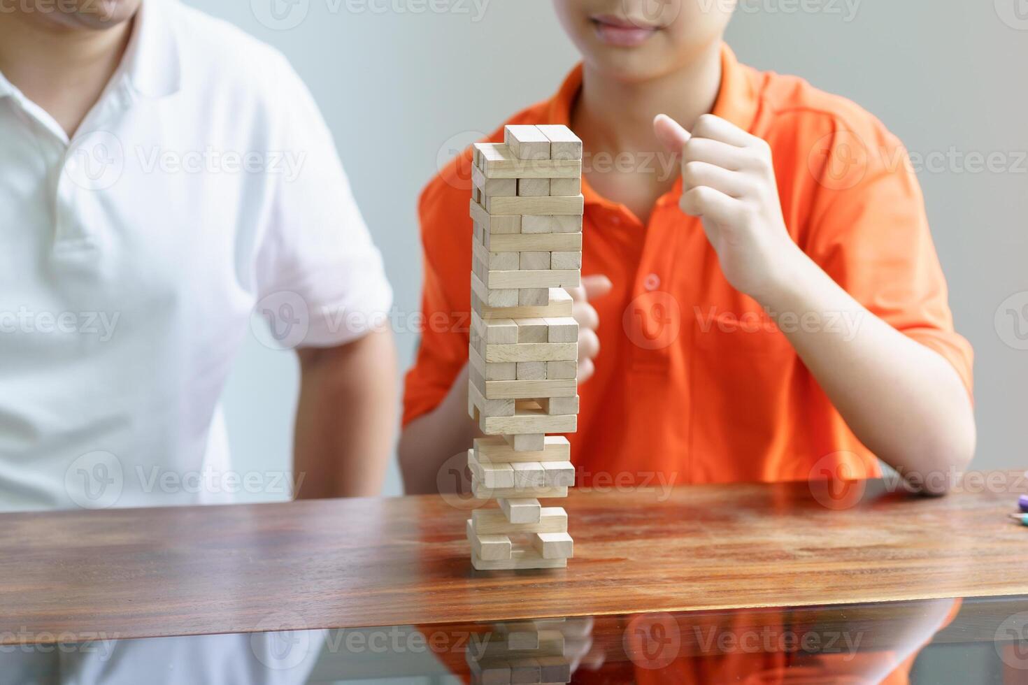 a boy and a man playing with wooden blocks on a table photo