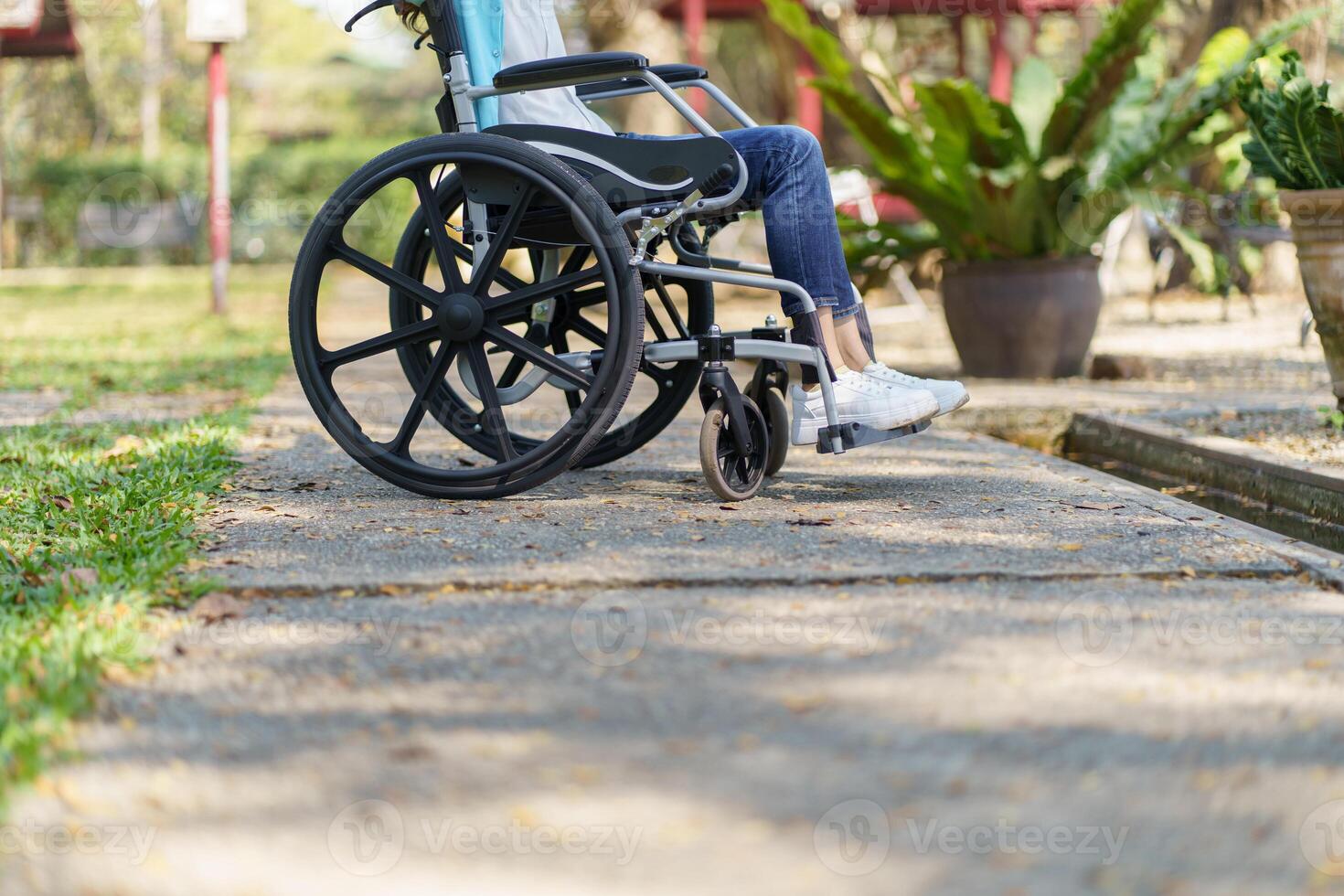 a woman in a wheelchair is sitting on the sidewalk photo