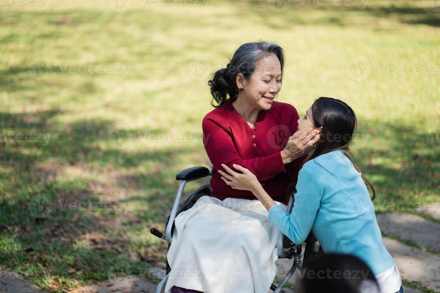 Asian senior woman in wheelchair with happy daughter. Family relationship retired woman sitting on wheelchair in park age care at retirement home photo