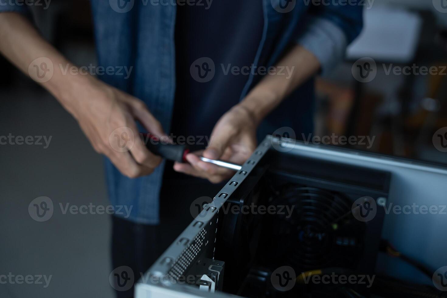 IT Engineer installing Hardware holding a screwdriver to a computer case photo