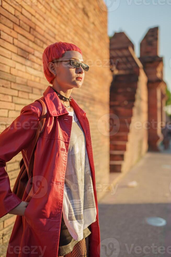 Gen z girl leather fashion with punk tourist of local city Southeast Asia travel trendy pink hairstyle young female punk traveler walking around in town photo
