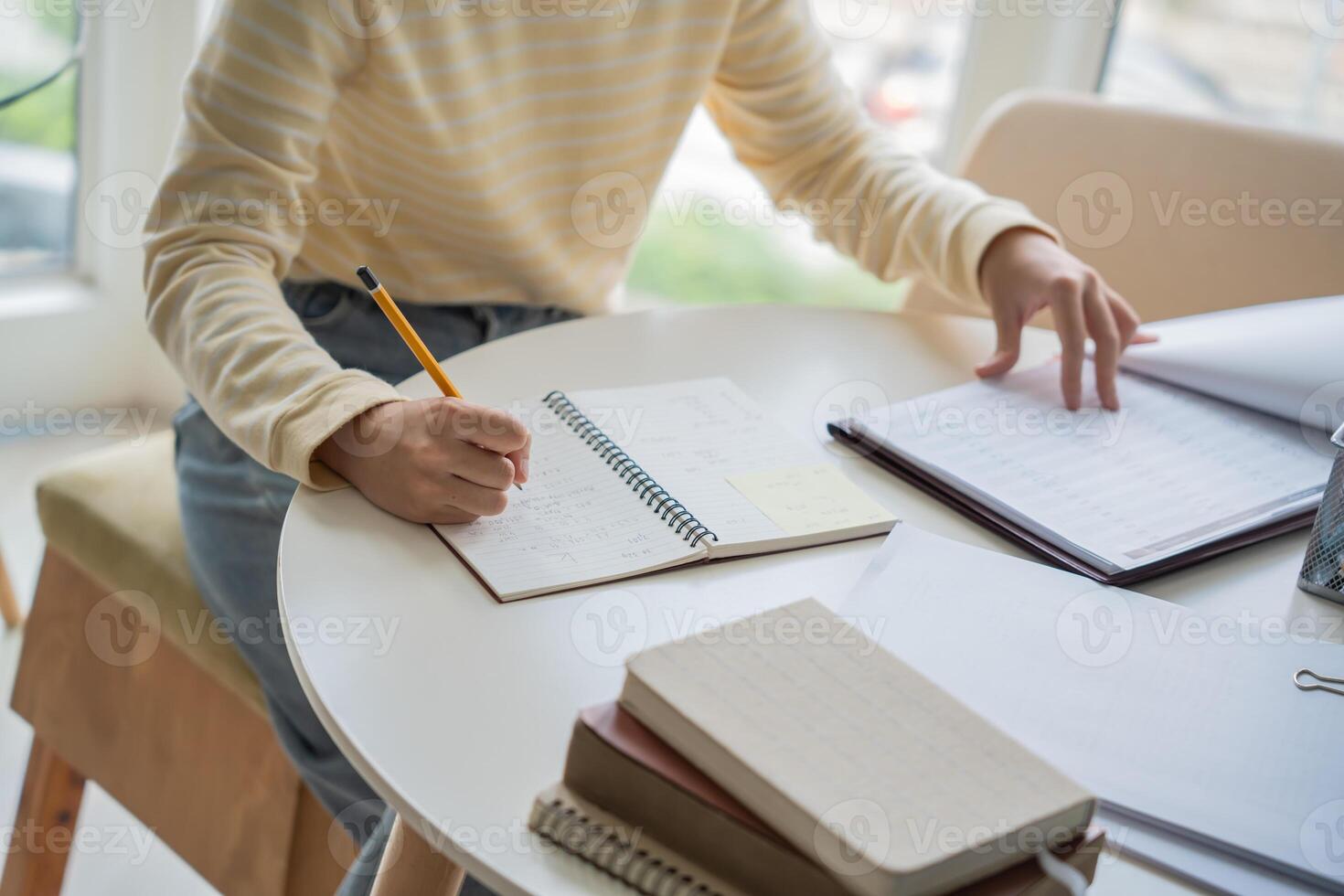 a Student is sitting at a table with a notebook and pen photo
