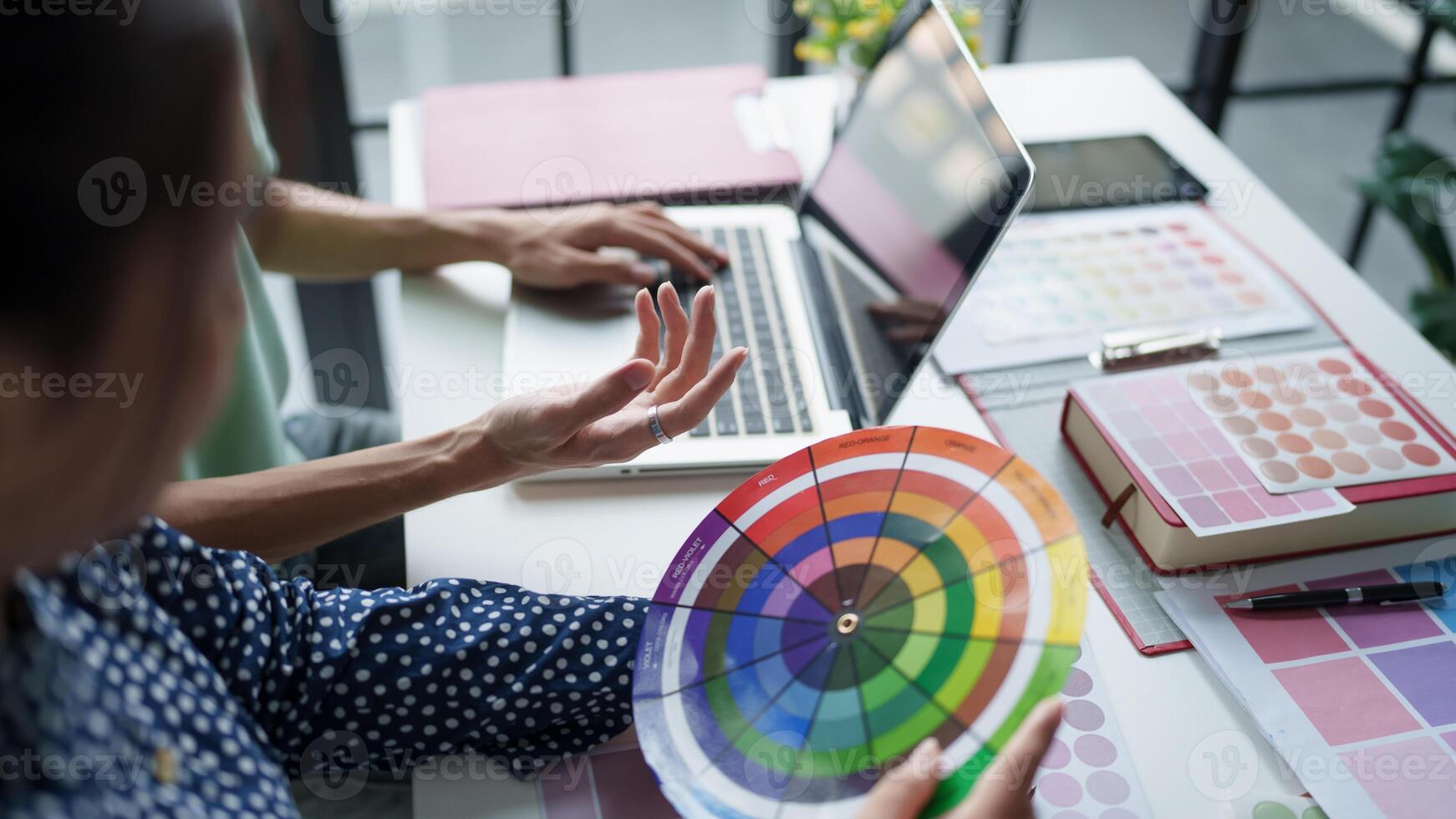 a woman is using a color wheel to choose a color for her laptop. photo